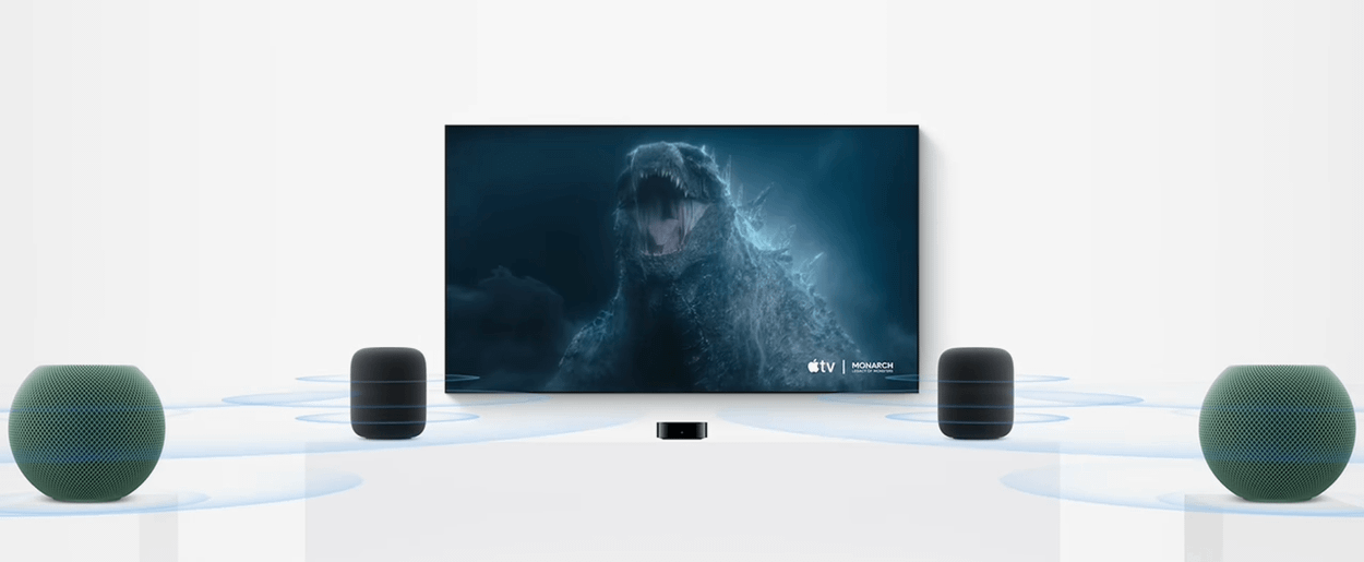 A modern flat-screen TV displaying a dark, monstrous creature with glowing blue highlights, flanked by four smart speakers emitting blue sound waves. The background is bright and minimalistic, highlighting the audio-visual setup.