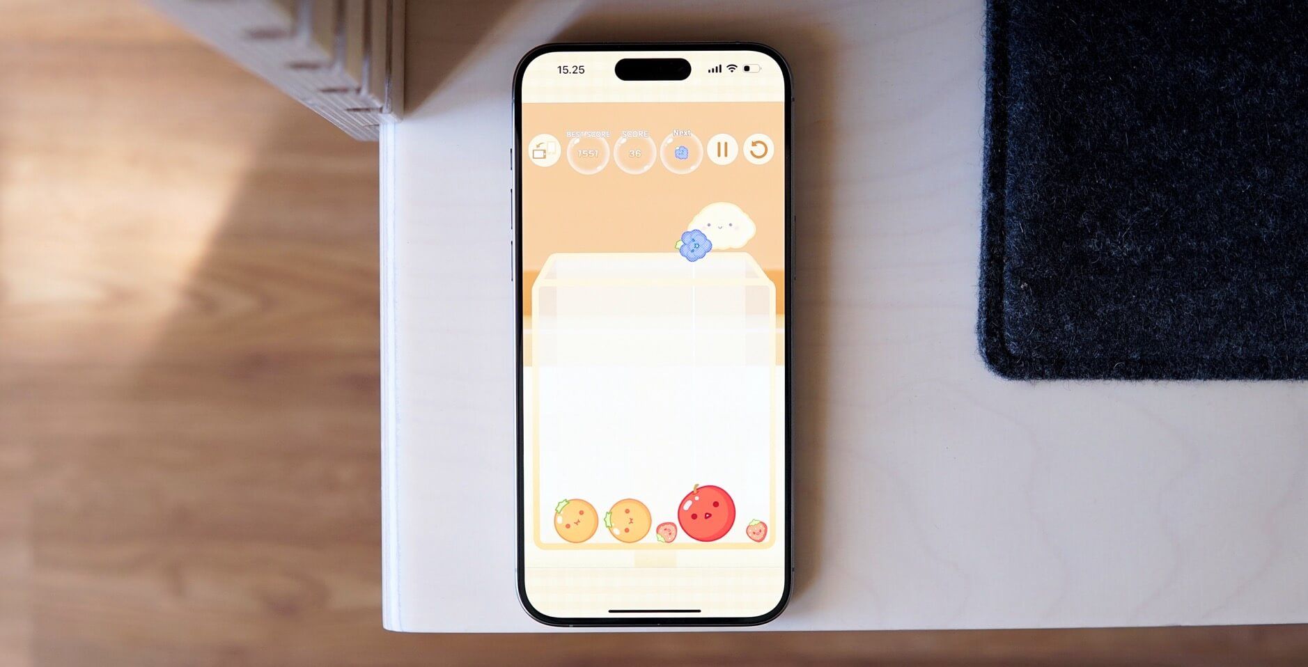 Bild zeigt Suika Game auf einem iPhone 15 Pro Max, das auf einem Schreibtisch liegt.