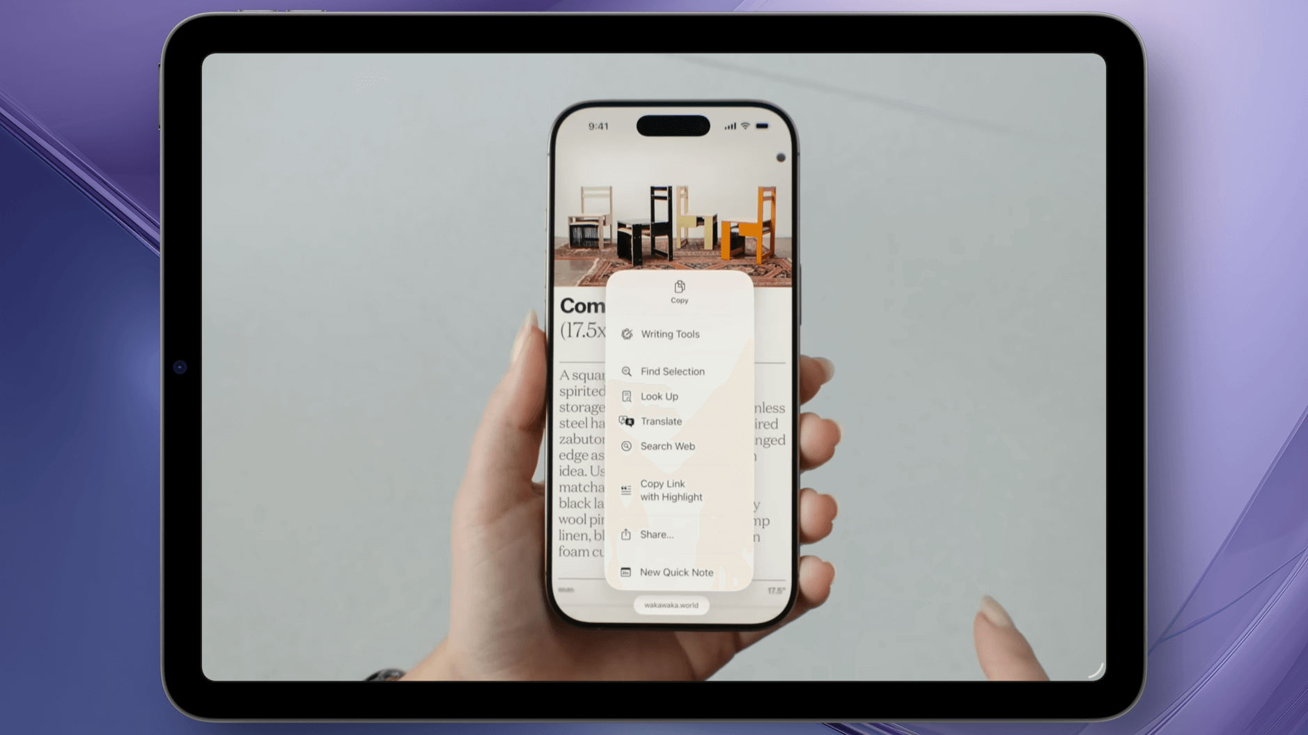 Eine Hand hält ein iPhone, auf dessen Bildschirm ein Kontextmenü mit verschiedenen Optionen wie „Writing Tools“, „Look Up“, „Translate“ und „Search Web“ angezeigt wird. Im Hintergrund ist ein Artikel mit einem Bild von mehreren Stühlen zu sehen. Das iPhone wird vor einem hellen, unscharfen Hintergrund gehalten.