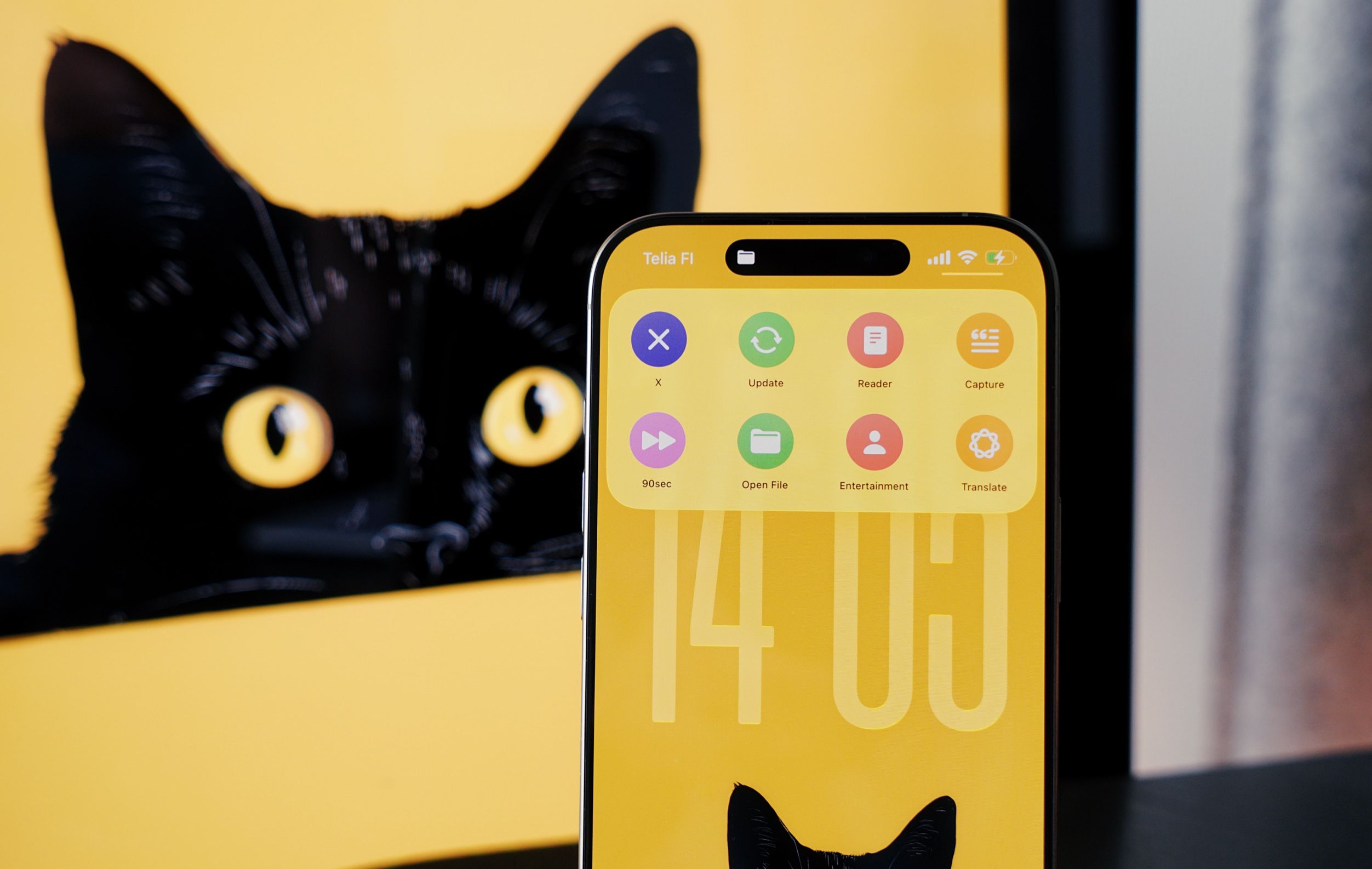 A modern smartphone displaying a custom interface on a yellow background with a digital cat's head design, a real image of a black cat's eyes in the background.
