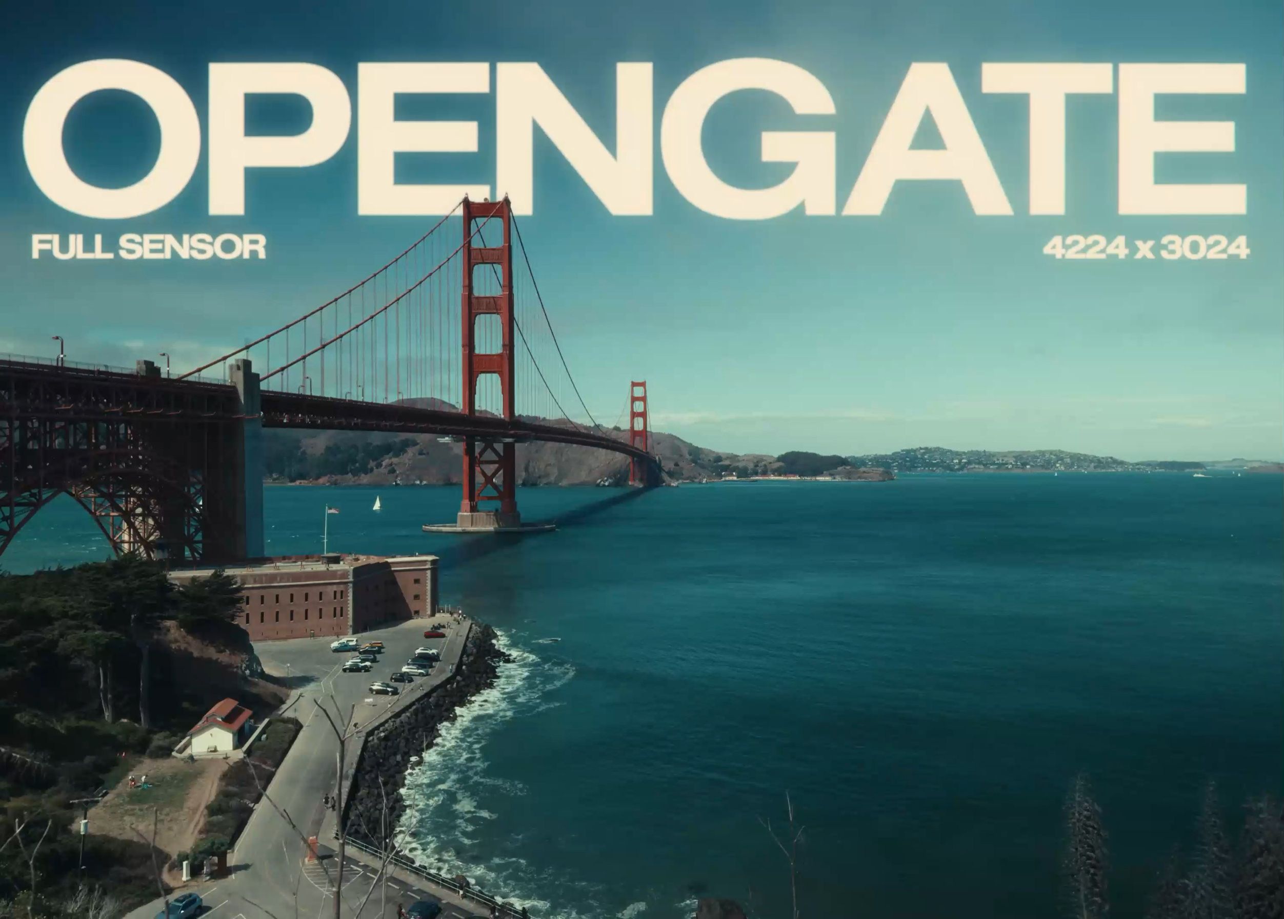 Aerial view of the Golden Gate Bridge in San Francisco, California, showcasing the iconic red suspension bridge spanning across the bay, with a sky-blue backdrop. Large white text "OPENGATE" with "FULL SENSOR" and "4224 x 3024" text displayed at the top. The view includes the water, land, buildings, and a coastal road.
