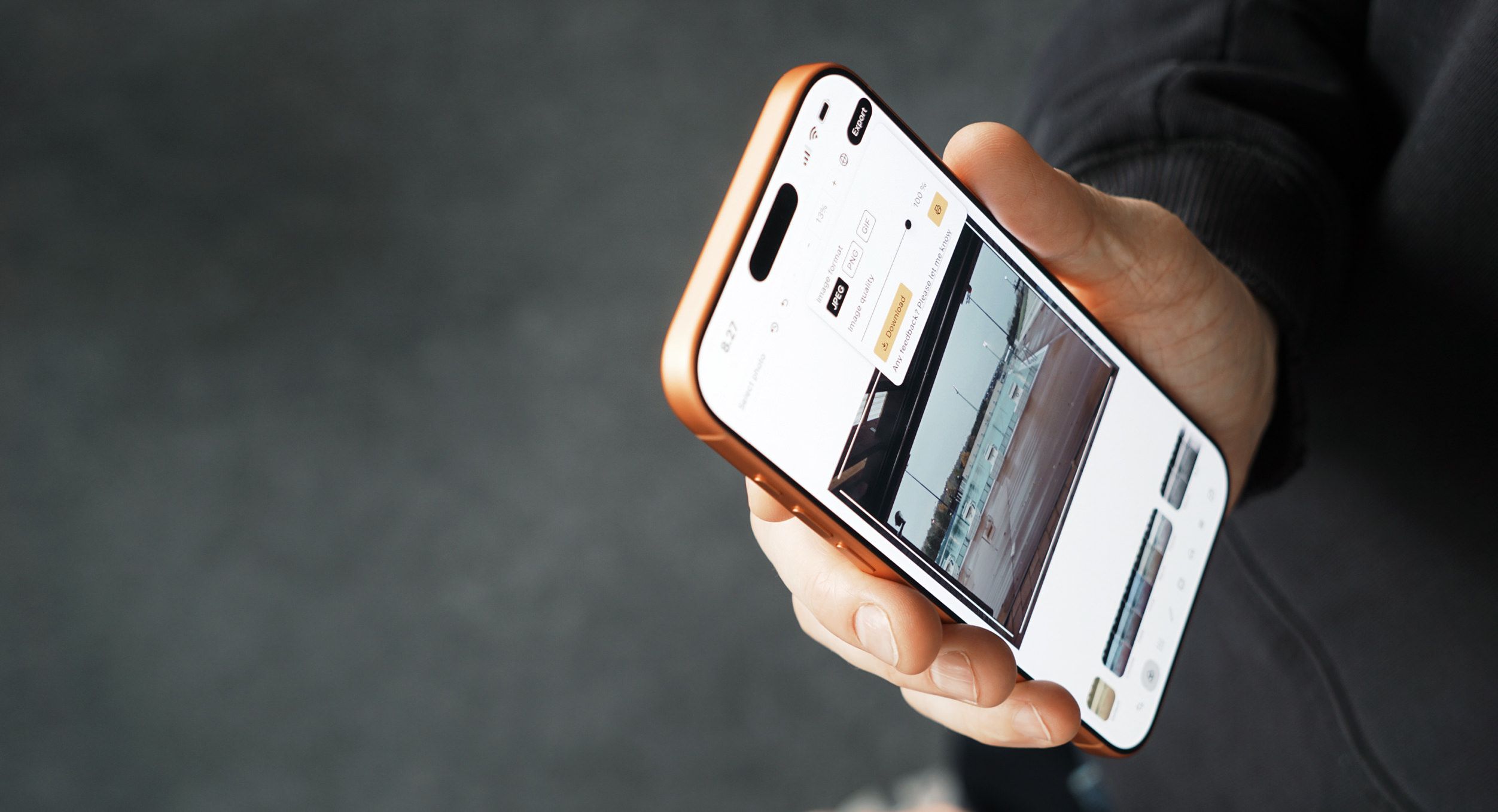 A person's hand holding a gold-colored smartphone with a screen displaying photo export options: image format selection and quality, including a preview of the selected photo. The background is a dark gray gradient.
