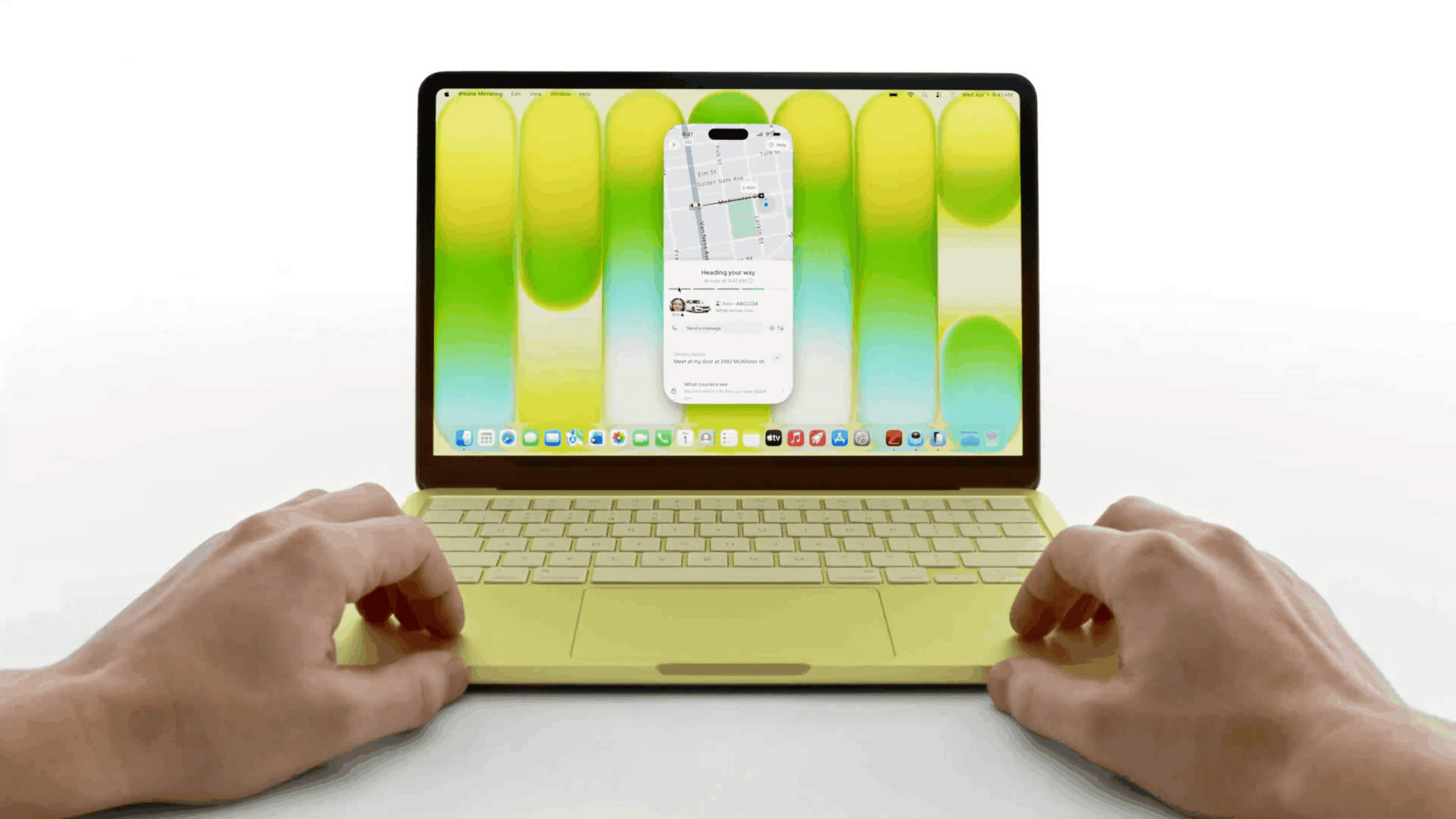 Ein gelber Laptop ist geöffnet und spiegelt die Anzeige eines Smartphones auf seinem Bildschirm wider. Auf dem Bildschirm ist eine Navigations-App mit dem Text "Unterwegs", zusammen mit einem Autosymbol und dem Namen "Alex ABC1234" zu sehen. Die Tastatur des Laptops ist im Fokus, mit zwei Händen, die sich in der Nähe des Trackpads befinden.