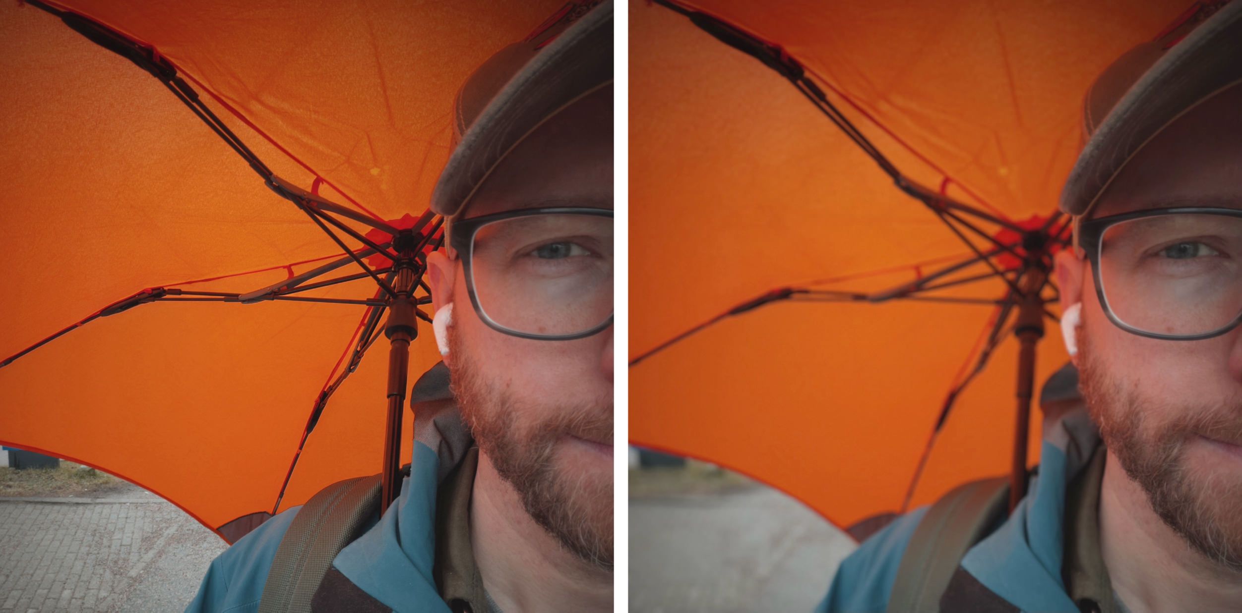 Ein Mann mit Bart, Brille und Hut, der einen orangefarbenen Regenschirm hält, aus der Perspektive eines Selfies gesehen.