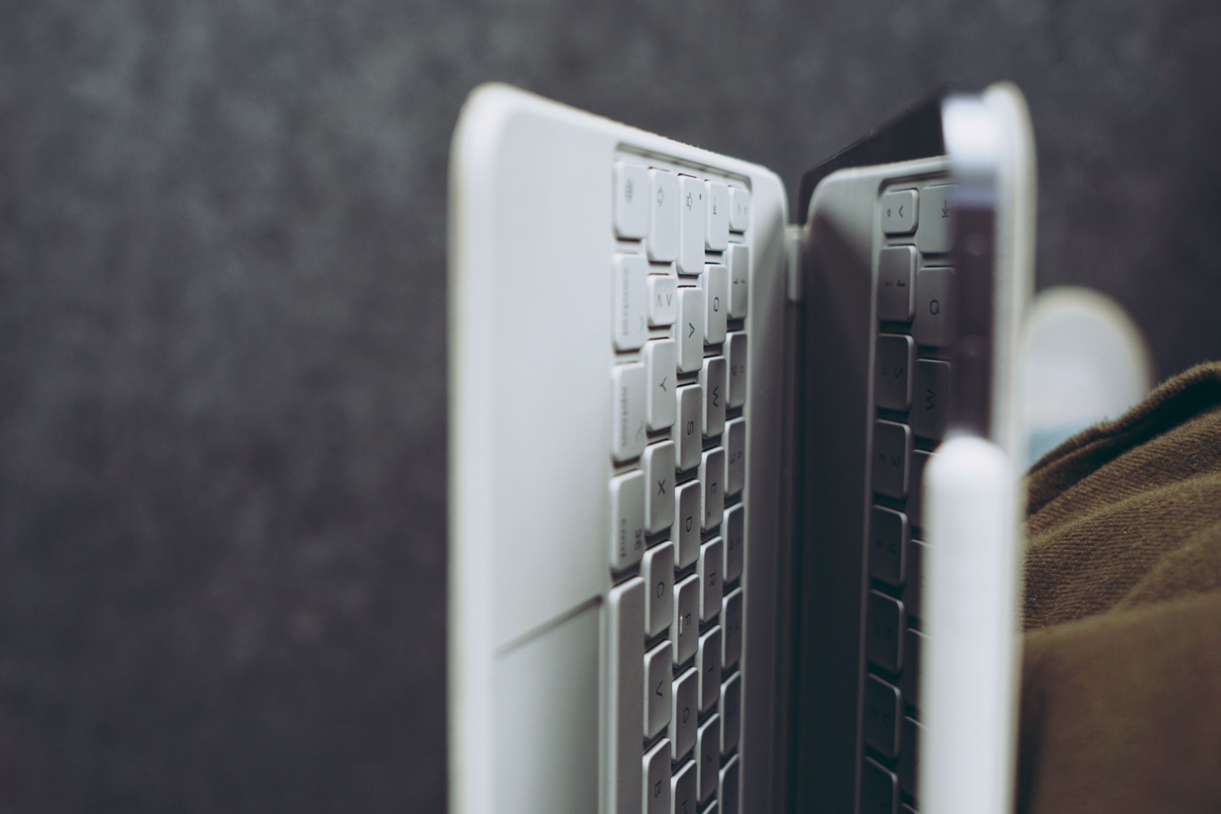 Nahaufnahme in der Seitenansicht einer weißen Tablet-Tastaturhülle, die an einem Tablet befestigt ist, vor einem verschwommenen, dunklen Hintergrund.