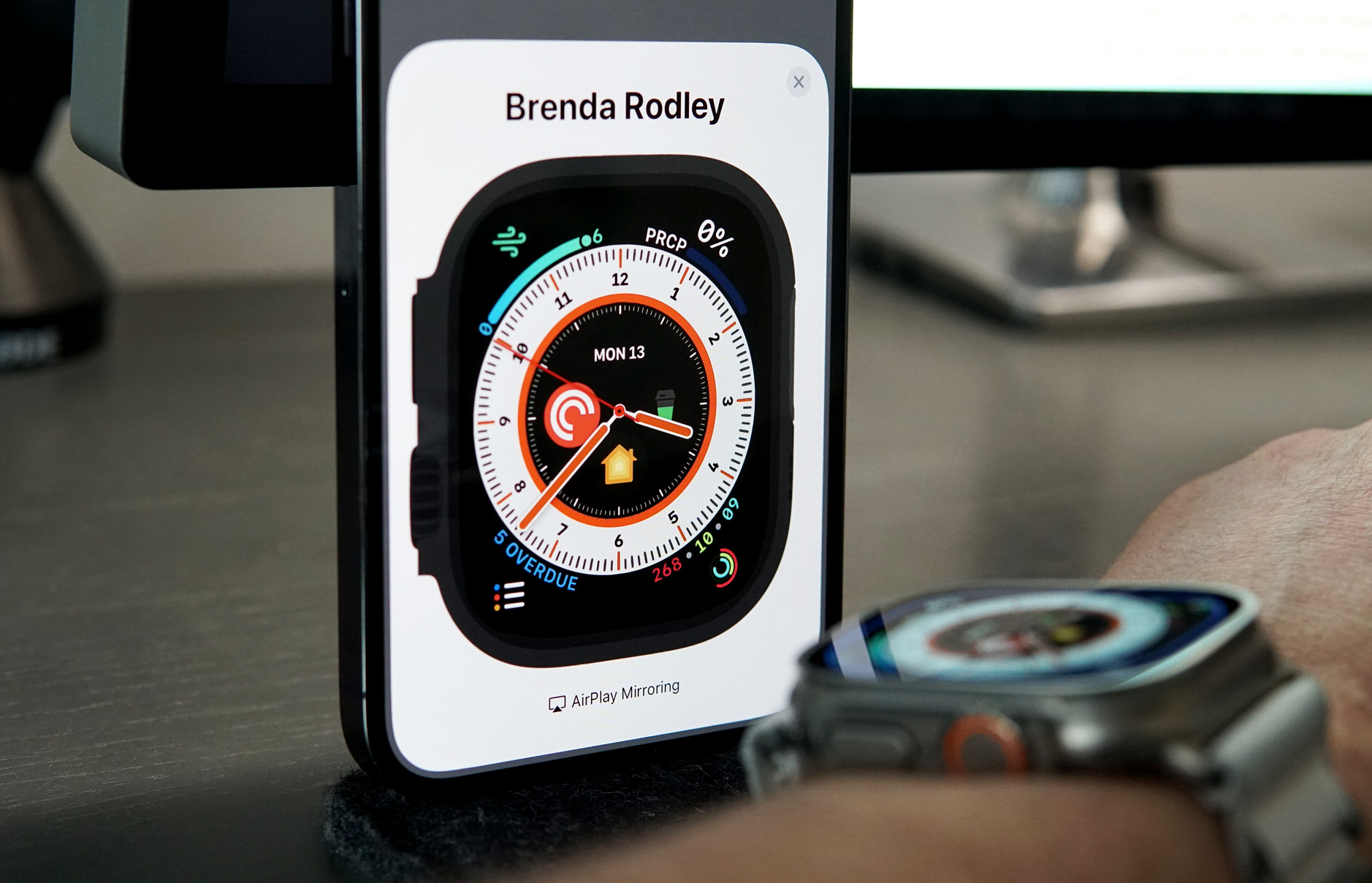 Bild zeigt Apple-Watch-Bildschirm auf iPhone mit Apple Watch am Armgelenk davor.