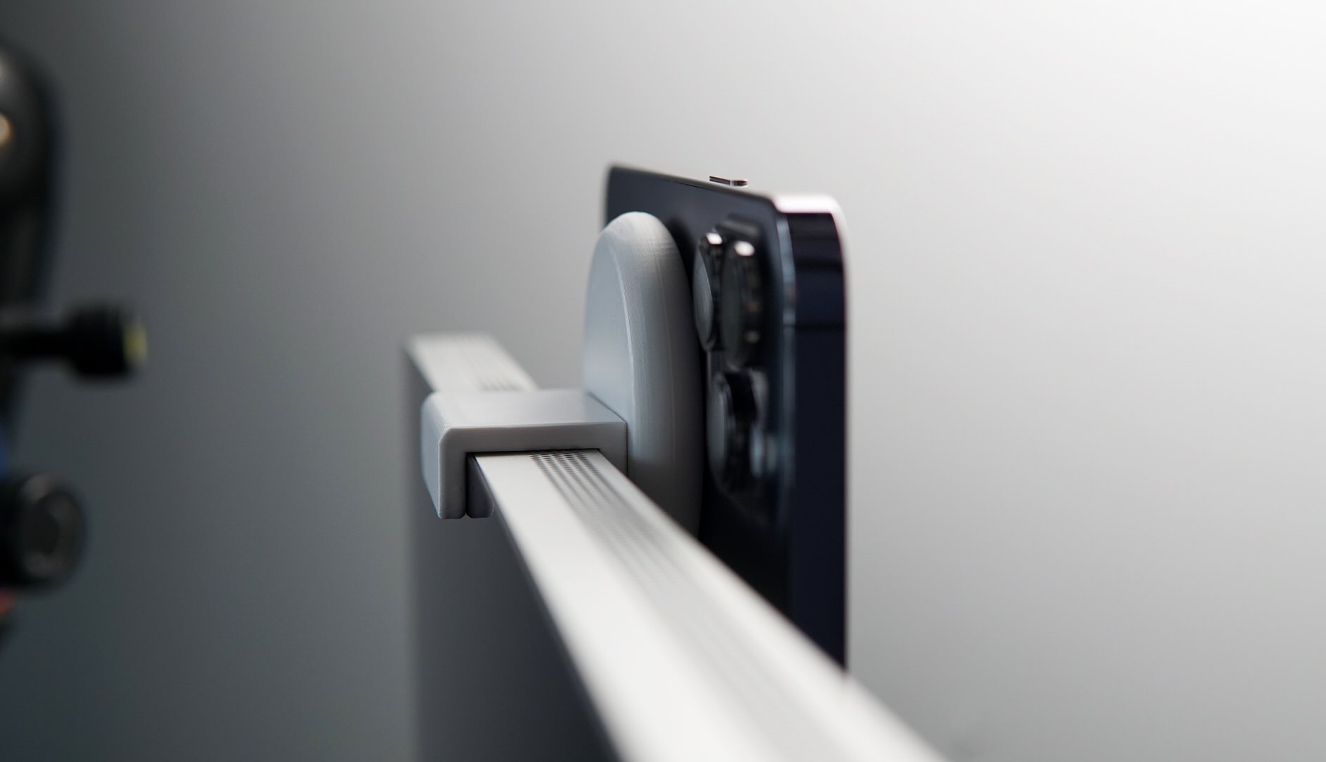 Bild zeigt iPhone, das an der Oberseite vom Monitor hängt.