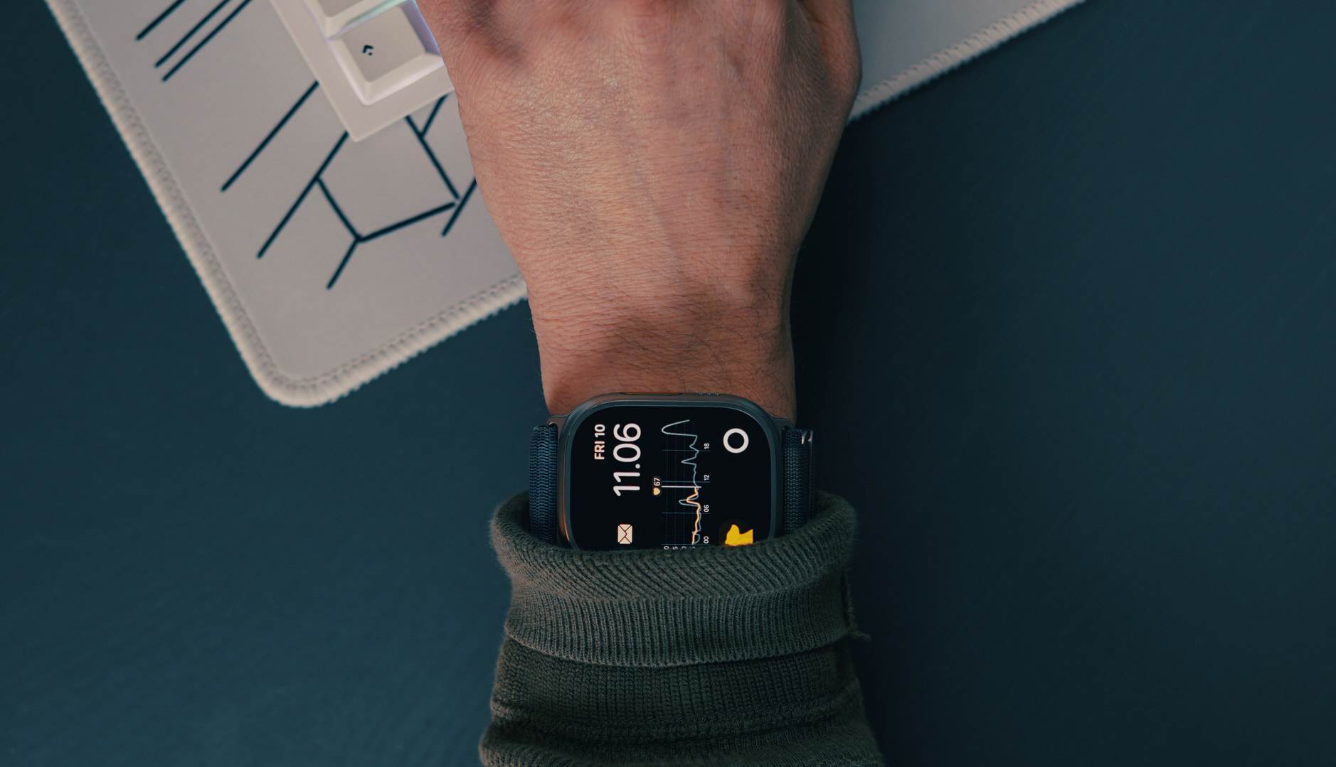 Apple Watch Ultra 2 an Handgelenk auf Schreibtisch.