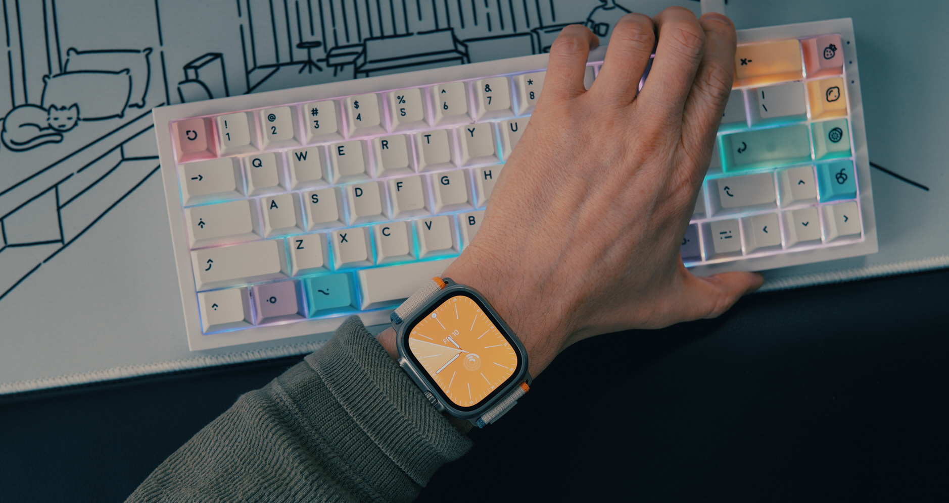Vogelperspektive auf Schreibtisch mit Apple Watch Ultra 2 an Handgelenk und Tastatur.