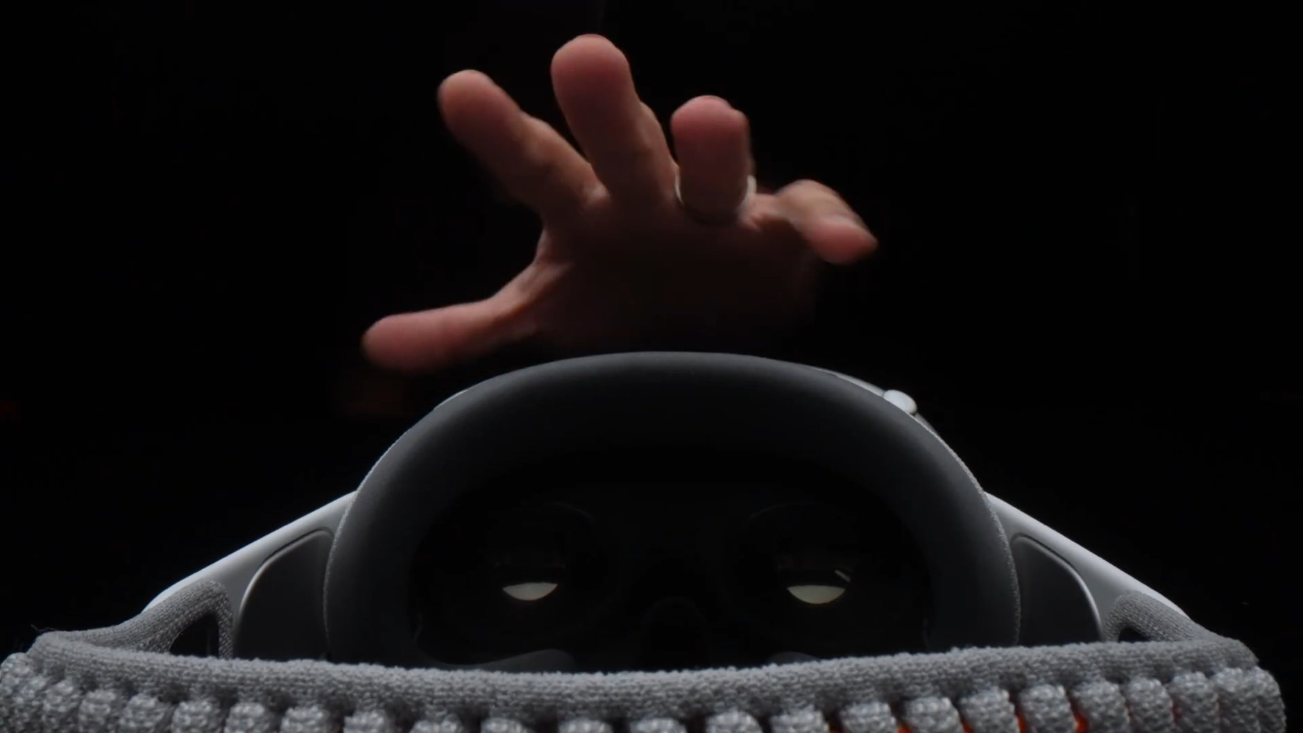 Screenshot aus dem Video von The Verge. Hand greift nach Apple Vision Pro.