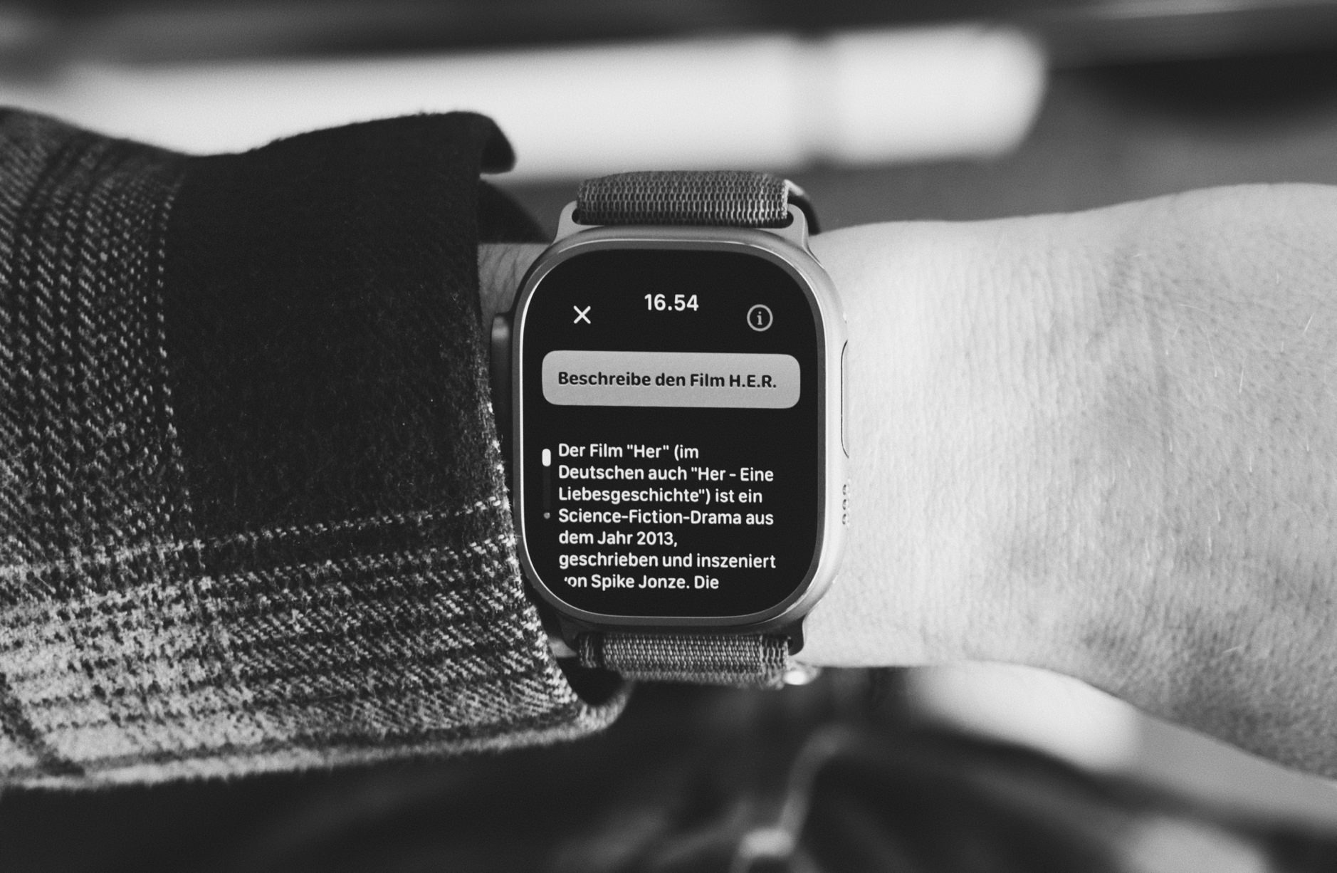 Apple Watch Ultra an Handgelenk zeigt eine Suchanfrage über Petey.