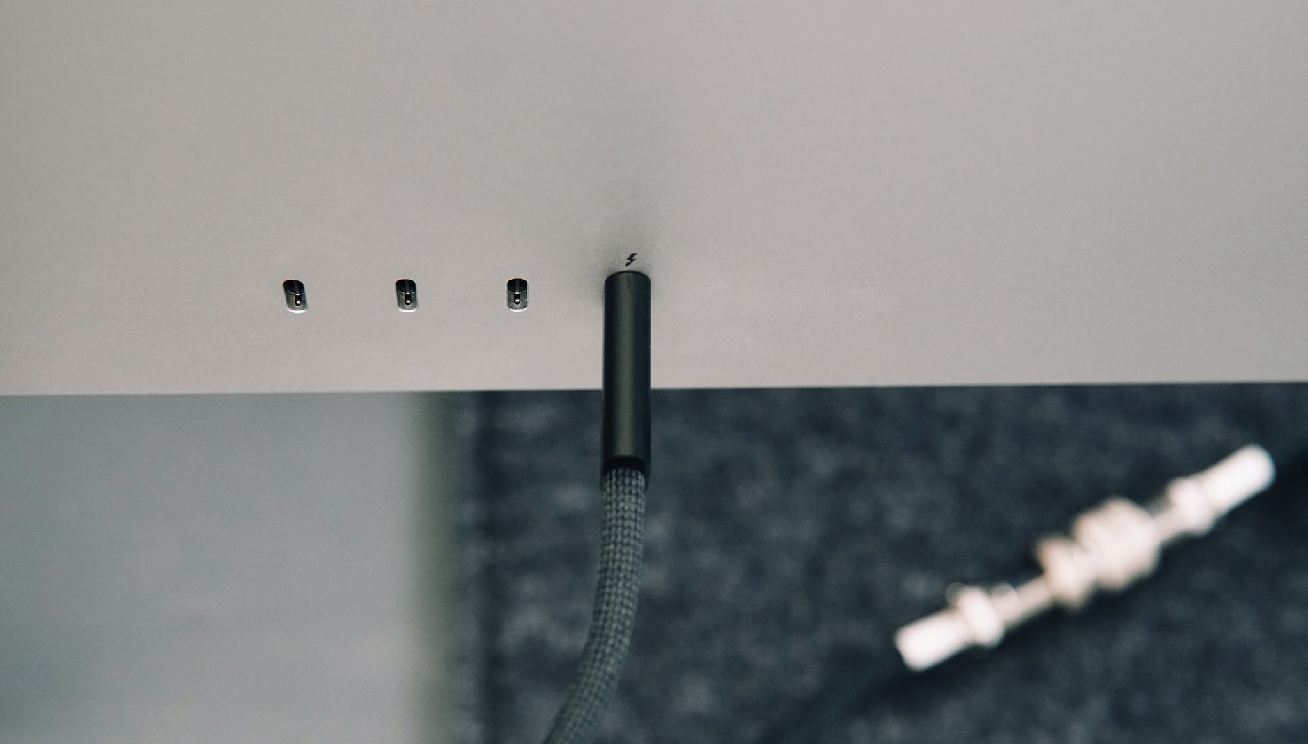 Bild zeigt Rückseite des Apple Studio Display mit eingestecktem Thunderbolt-4-Kabel.