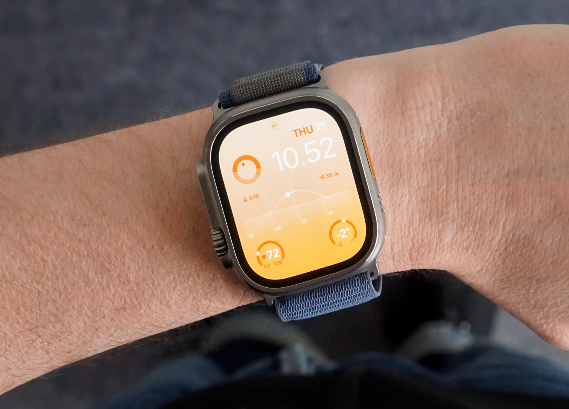 Auf dem Bild ist eine Apple Watch an einem Handgelenk zu sehen. Das Zifferblatt zeigt die Uhrzeit, das Datum, Schritte, die Herzfrequenz und das Wetter.