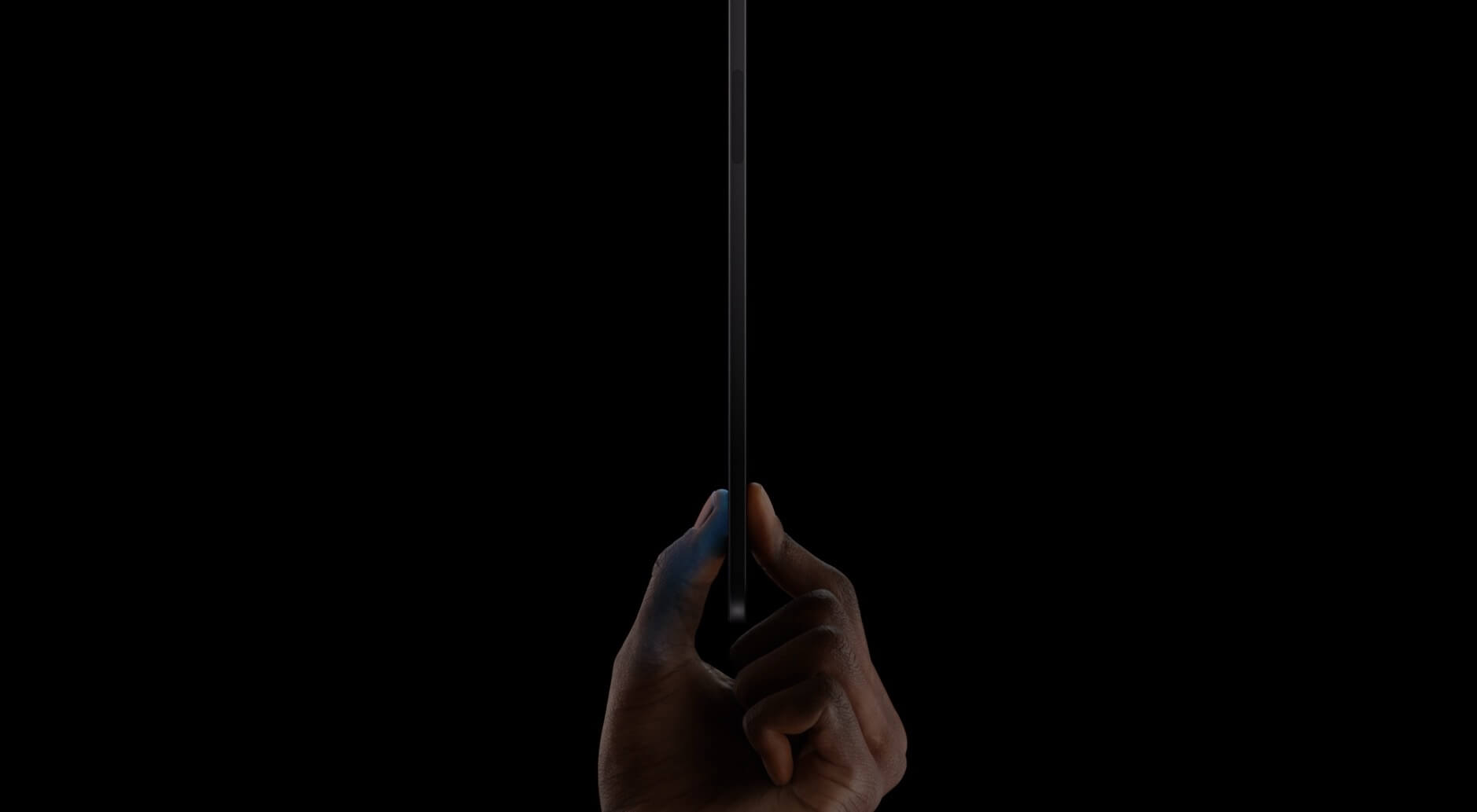 Das Bild zeigt eine Hand, die ein neues iPad Pro zwischen Daumen und Zeigefinger hält, vor einem dunklen Hintergrund.