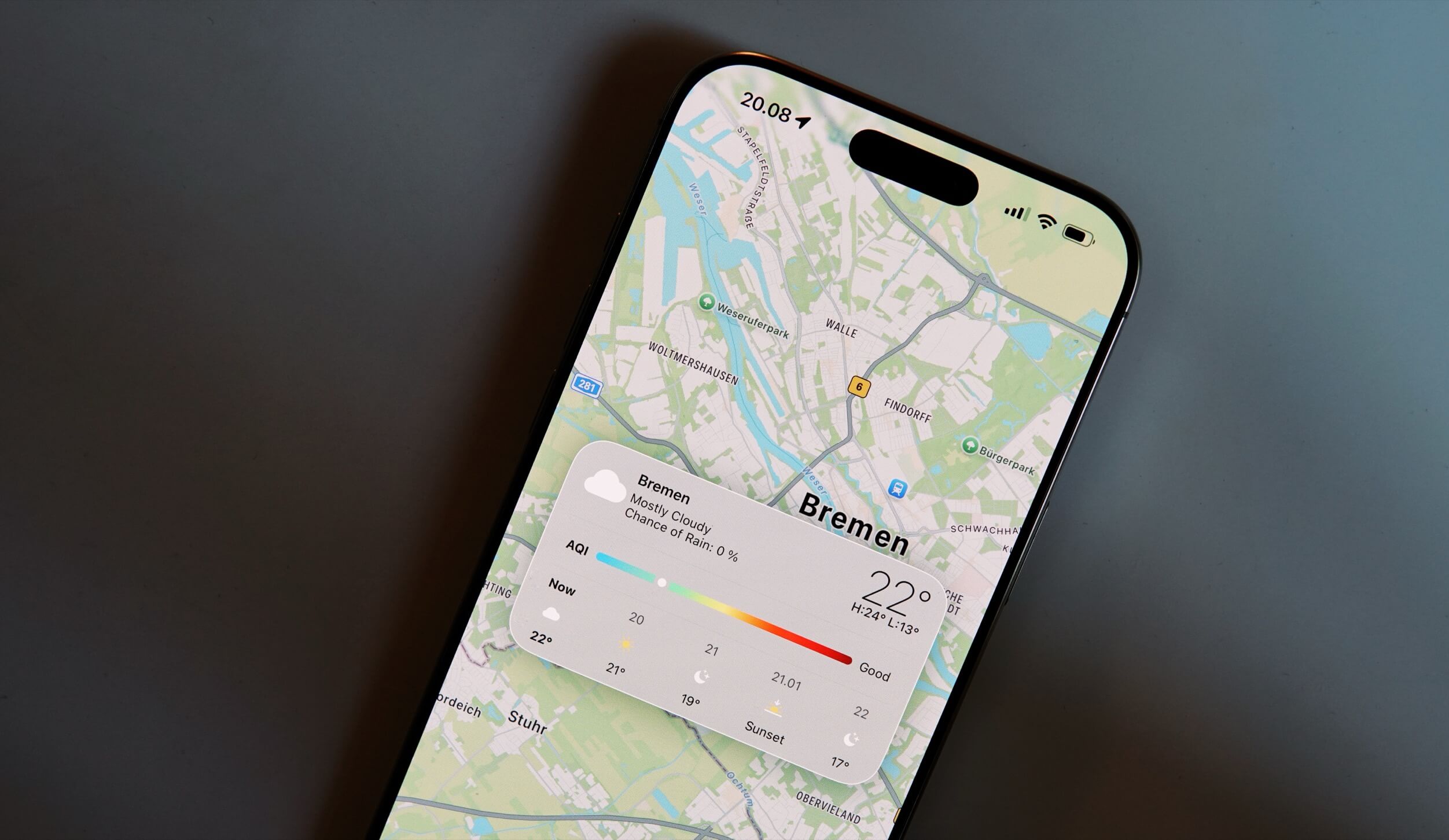 An iPhone displaying the weather forecast for Bremen, Germany, on the Weather app, with a map of the city visible in the background and current temperature details overlaid on the screen.
