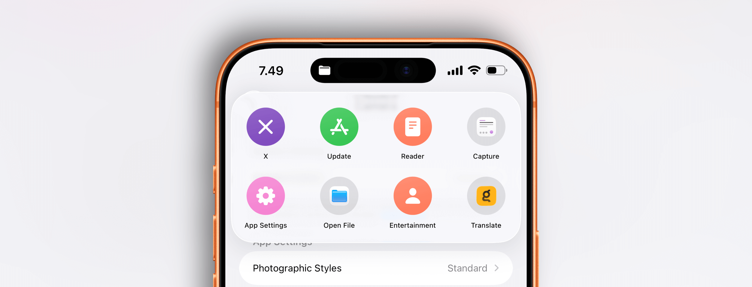 Close-up of an orange iPhone screen displaying a menu of app icons, with the time and status bar visible, including a "Dynamic Island" notch, showing the "X", "Update", "Reader", "Capture", "App Settings", "Open File", "Entertainment", and "Translate" apps, and a "Photographic Styles" menu.
