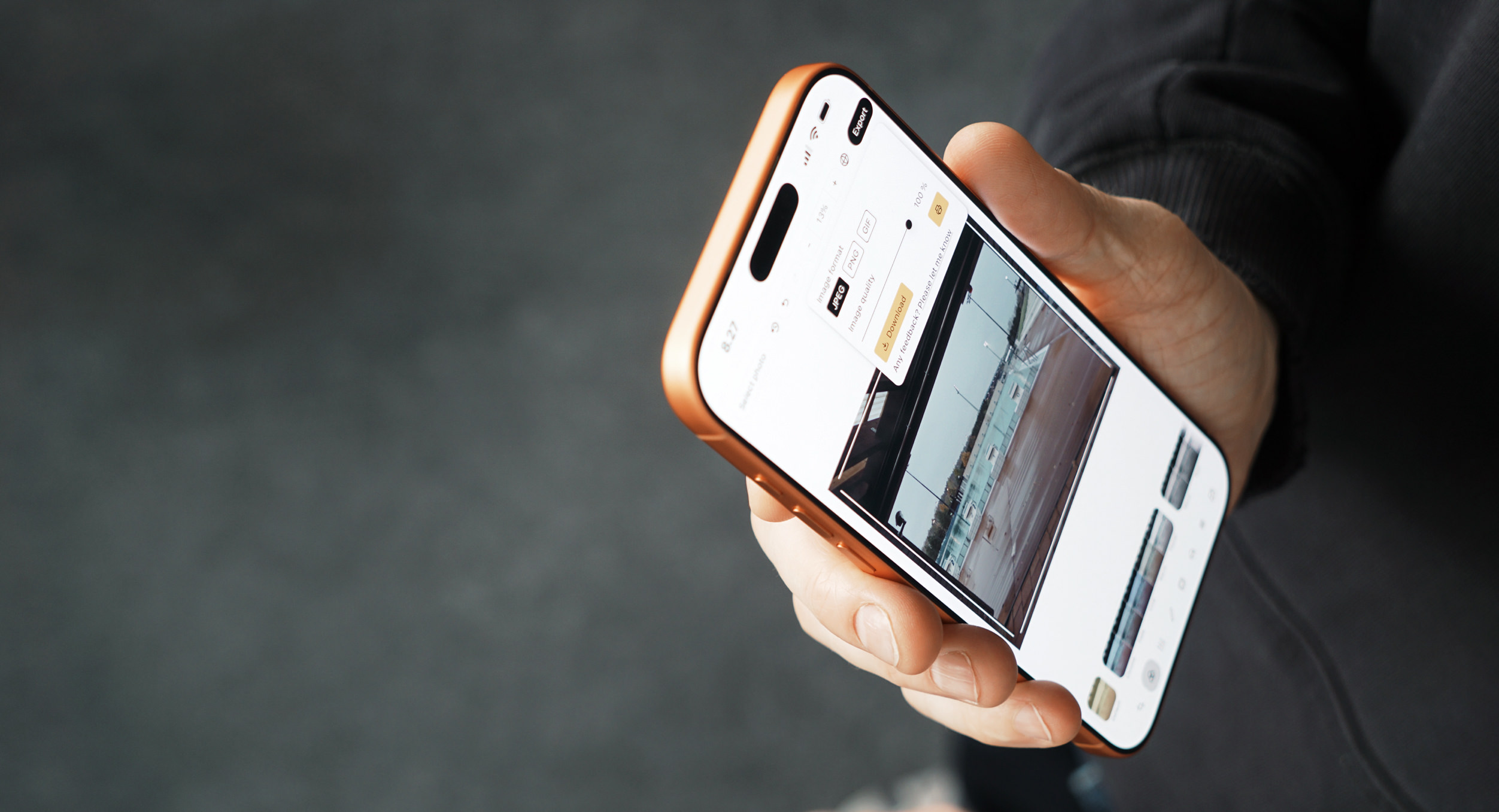 A person's hand holding a gold-colored smartphone with a screen displaying photo export options: image format selection and quality, including a preview of the selected photo. The background is a dark gray gradient.
