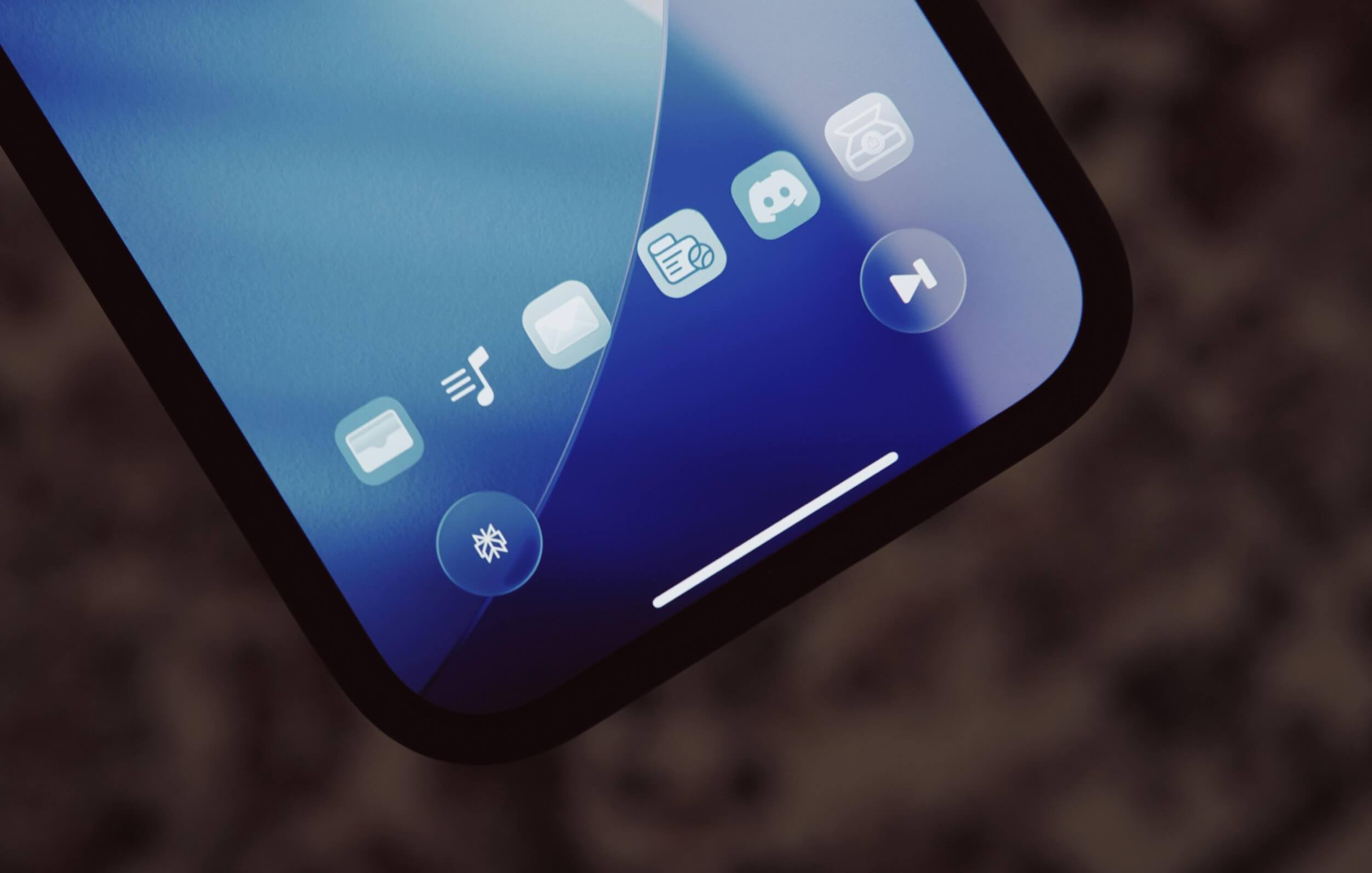 Nahaufnahme eines Smartphone-Bildschirms mit blauem Farbverlauf im Hintergrund. Auf dem Bildschirm sind Symbole für eine Kamera, Musik, eine E-Mail, Discord und eine Videosteuerung zu sehen. Der untere Teil des Bildschirms hat einen weißen Balken.

