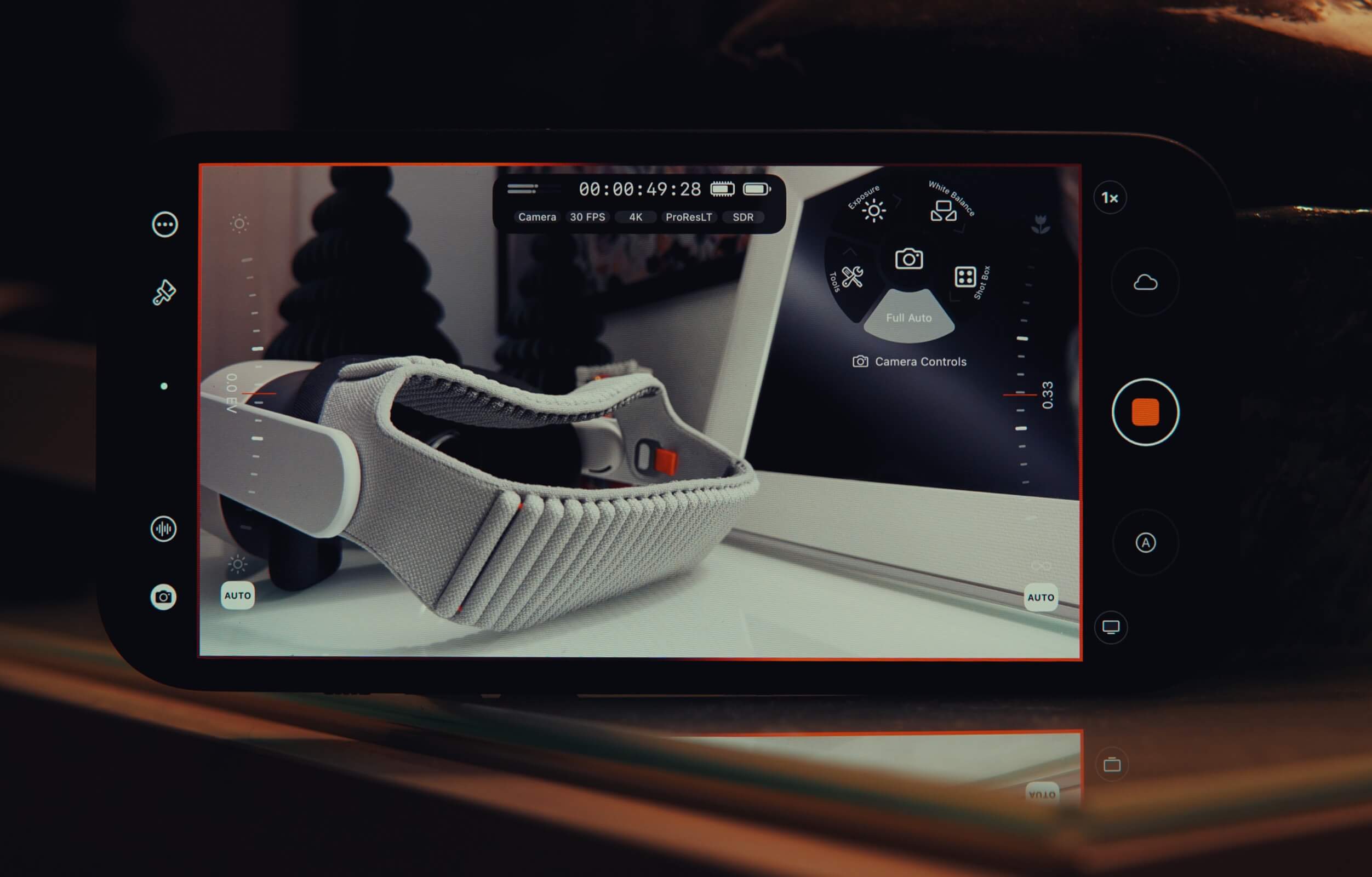 Ein Smartphone-Bildschirm zeigt eine Kamera-App-Oberfläche, die ein graues VR-Headset zeigt, das auf einem weißen Laptop liegt, wobei die App-Steuerelemente auf dem Display sichtbar sind.
