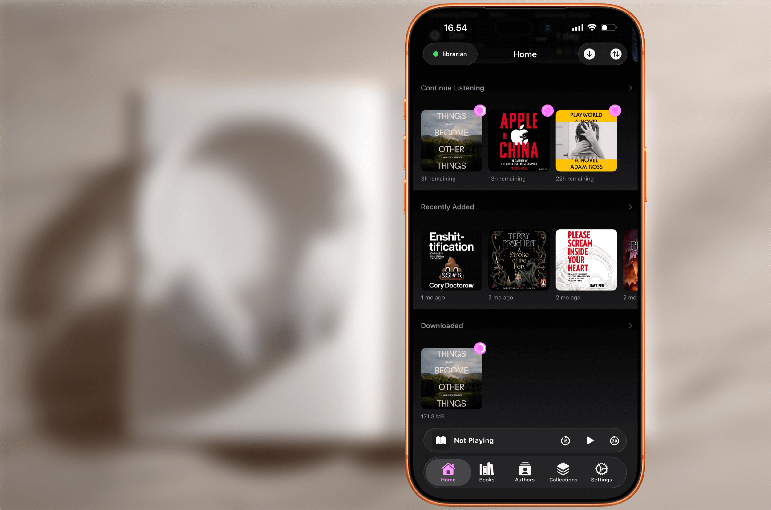 Ein Smartphone, das eine Benutzeroberfläche einer Dark-Theme-Hörbuch-App anzeigt und Buchcover mit Titeln wie "Things Become Other Things", "Apple in China" und "Playworld" auflistet.