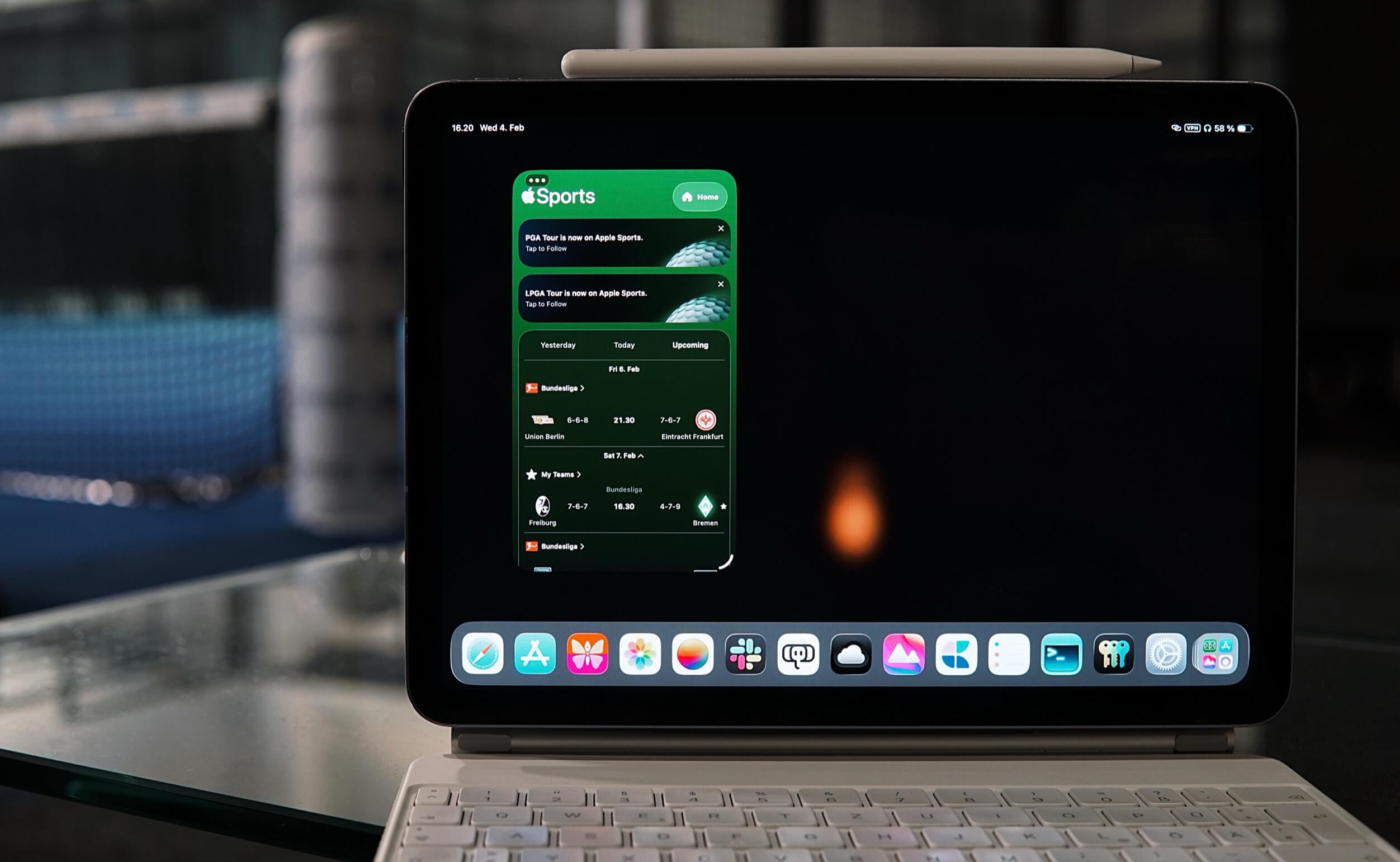 Ein iPad mit der Apple Sports App, die Live-Ergebnisse für Fußballspiele, eine Tastatur und einen Stift anzeigt.
