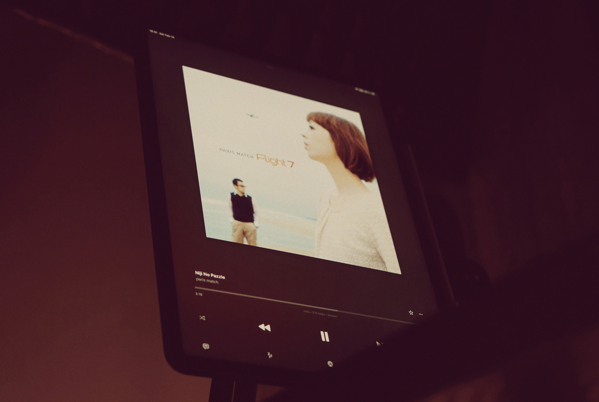 Tablet, das die Benutzeroberfläche einer Musik-App mit Albumcover von PARIS MATCHs Album "Flight 7" anzeigt und "Niji No Pazzle" abspielt.
