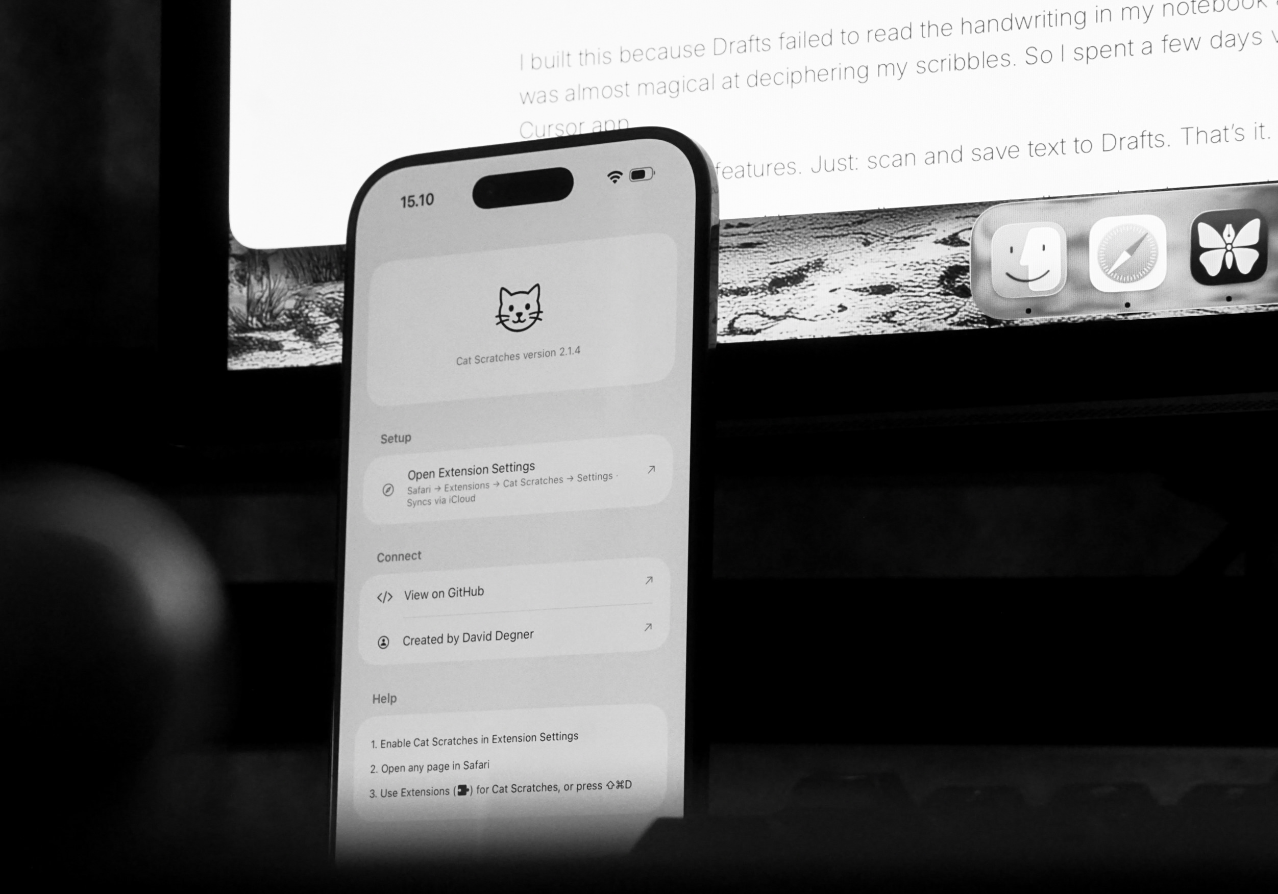 Ein Smartphone-Bildschirm, auf dem die Benutzeroberfläche der App "Cat Scratches" angezeigt wird. Das App-Symbol ist ein Katzenkopf mit Schnurrhaaren. Der Bildschirm zeigt "Cat Scratches version 2.1.4", ein Setup-Menü mit "Open Extension Settings", ein Connect-Menü mit "View on GitHub" und "Created by David Degner" sowie einen Hilfebereich mit Schritten. Hinter dem Telefon befindet sich ein Laptop-Bildschirm mit folgendem Text: "I built this because Drafts failed to read the handwriting in my notebook was almost magical at deciphering my scribbles. So I spent a few days Cursor app features. Just: scan and save text to Drafts. That's it."