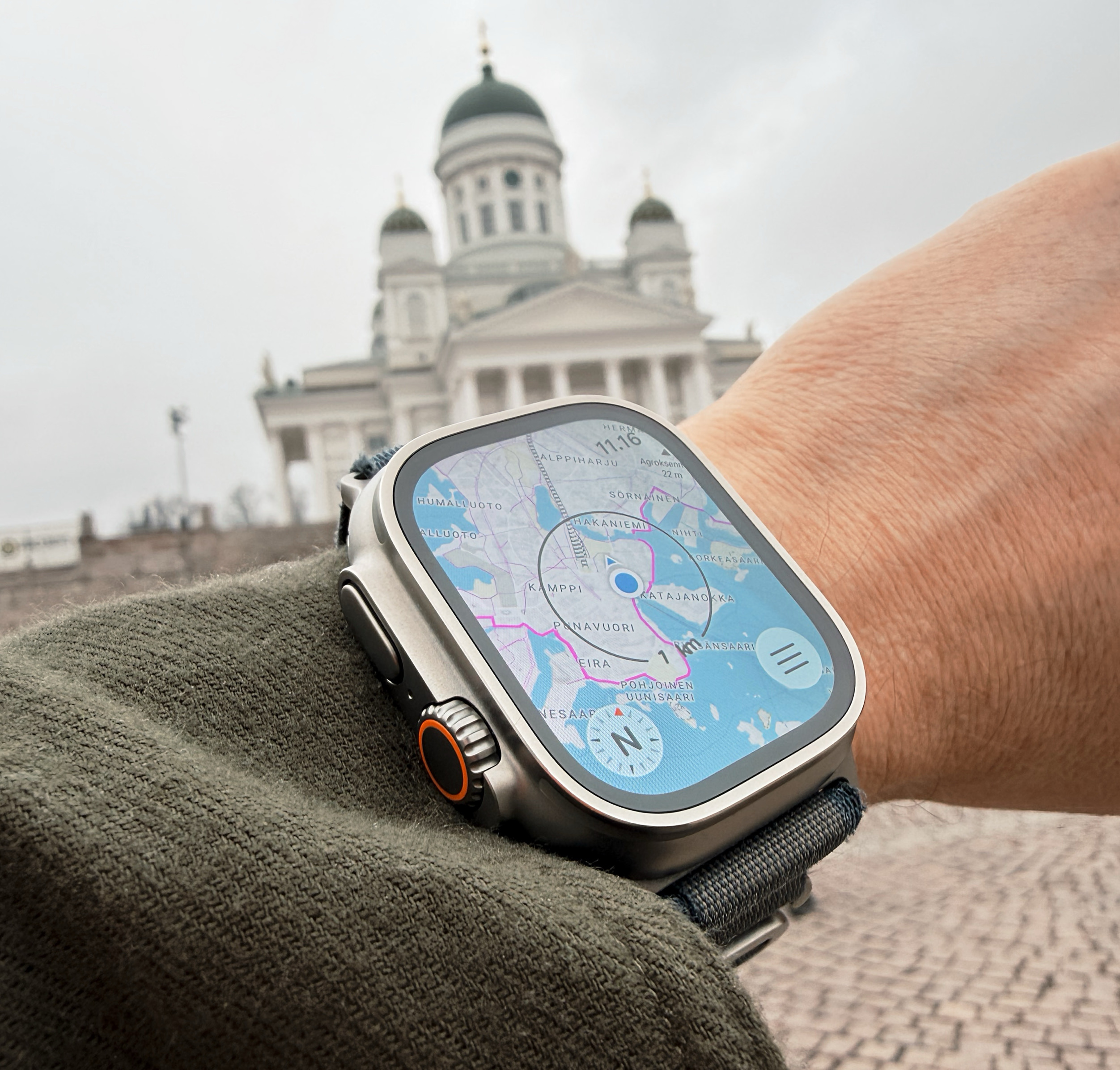 Eine Nahaufnahme einer Smartwatch am Handgelenk einer Person, die eine digitale Karte von Helsinki anzeigt, mit der Kathedrale von Helsinki im unscharfen Hintergrund.