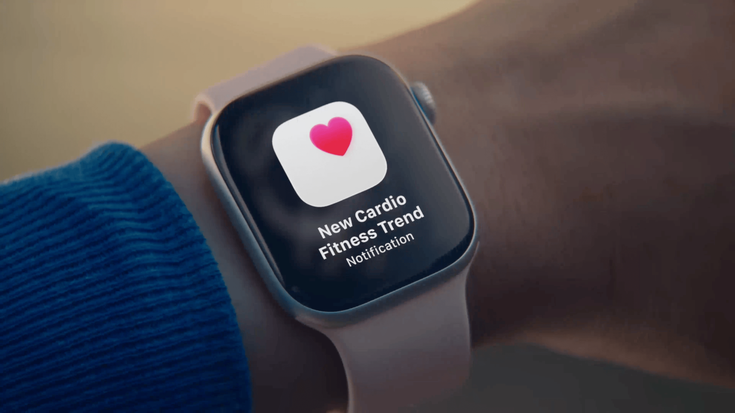 Eine Nahaufnahme einer Smartwatch am Handgelenk einer Person, die eine Benachrichtigung mit einem Herz-Symbol und dem Text „New Cardio Fitness Trend Notification“ anzeigt.