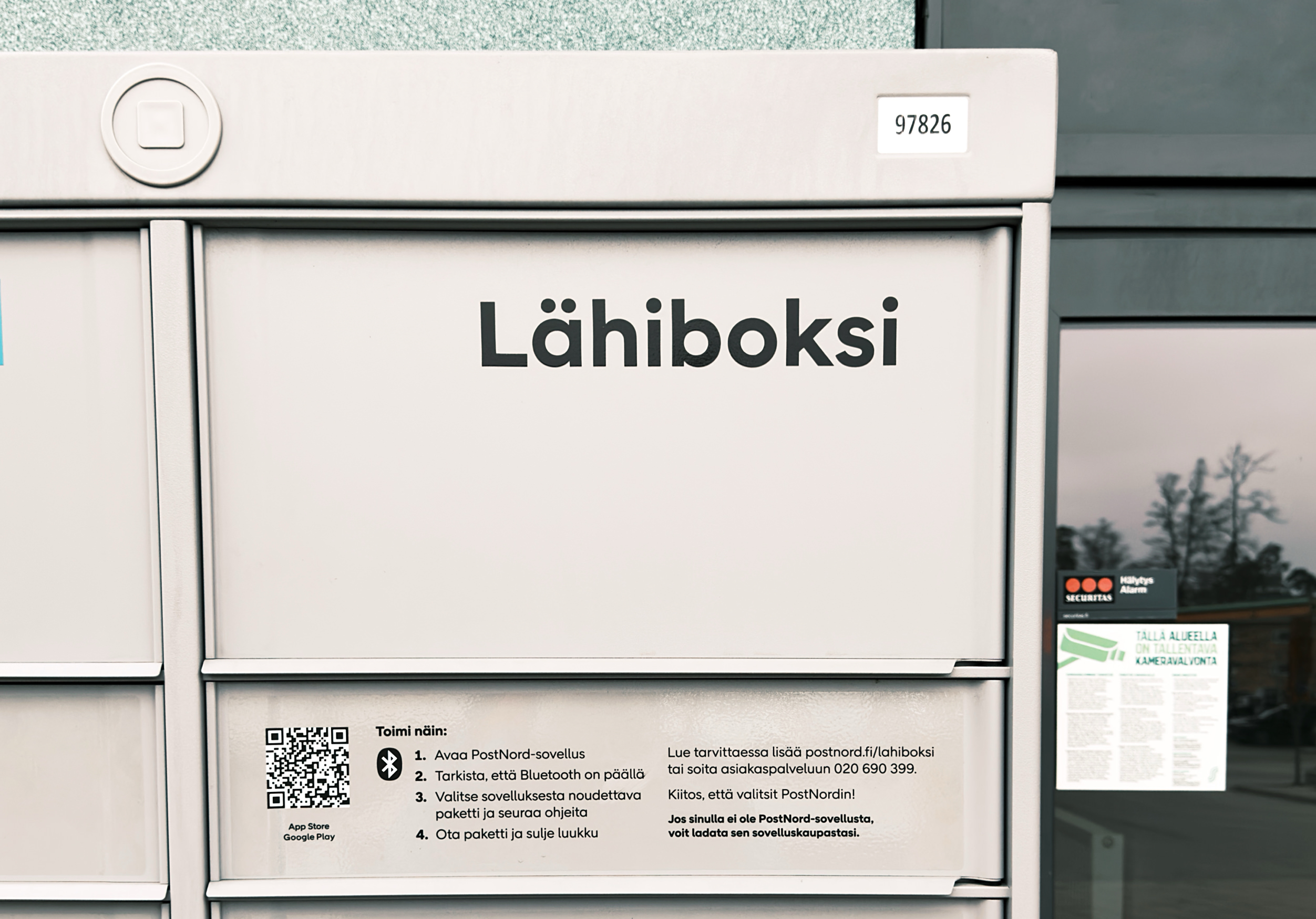 Eine Nahaufnahme eines grauen PostNord-Paketfachs. Der Text „Lähiboksi“ steht deutlich auf der Vorderseite.