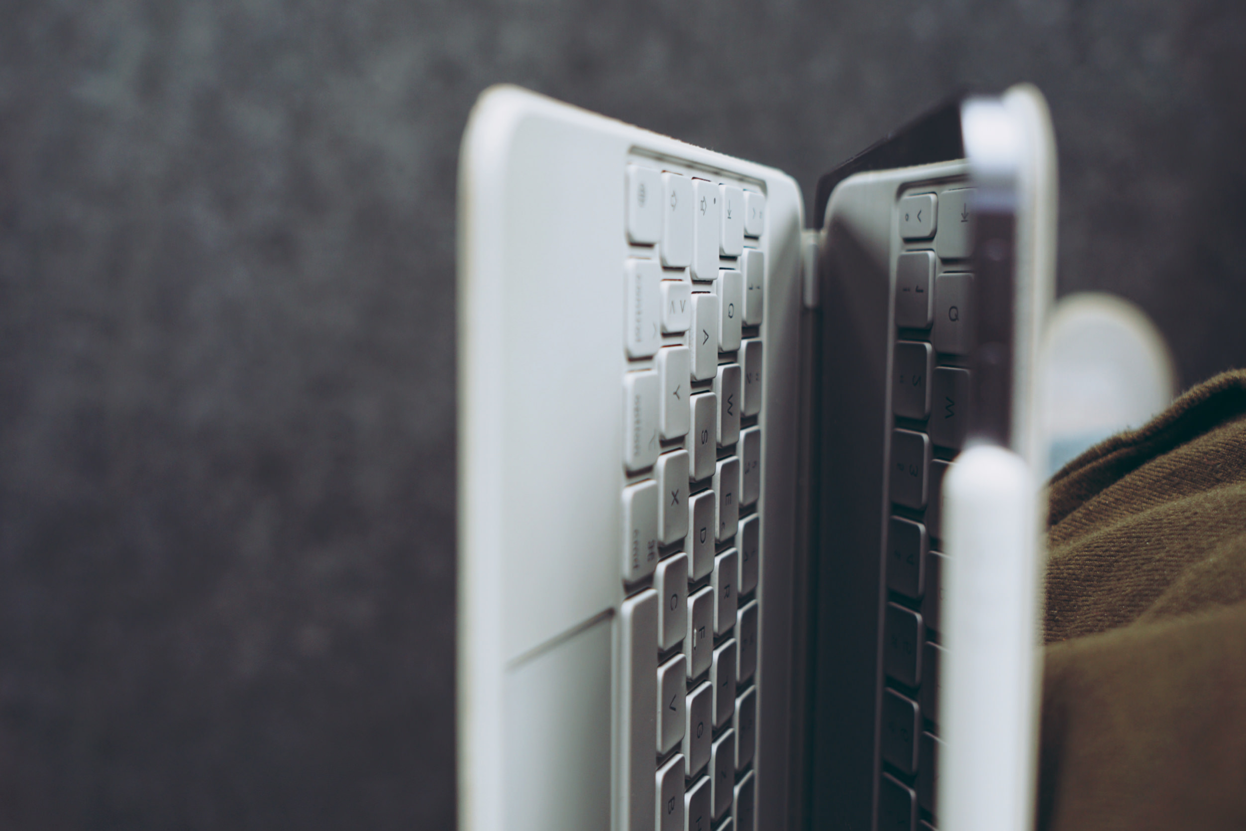 Nahaufnahme in der Seitenansicht einer weißen Tablet-Tastaturhülle, die an einem Tablet befestigt ist, vor einem verschwommenen, dunklen Hintergrund.