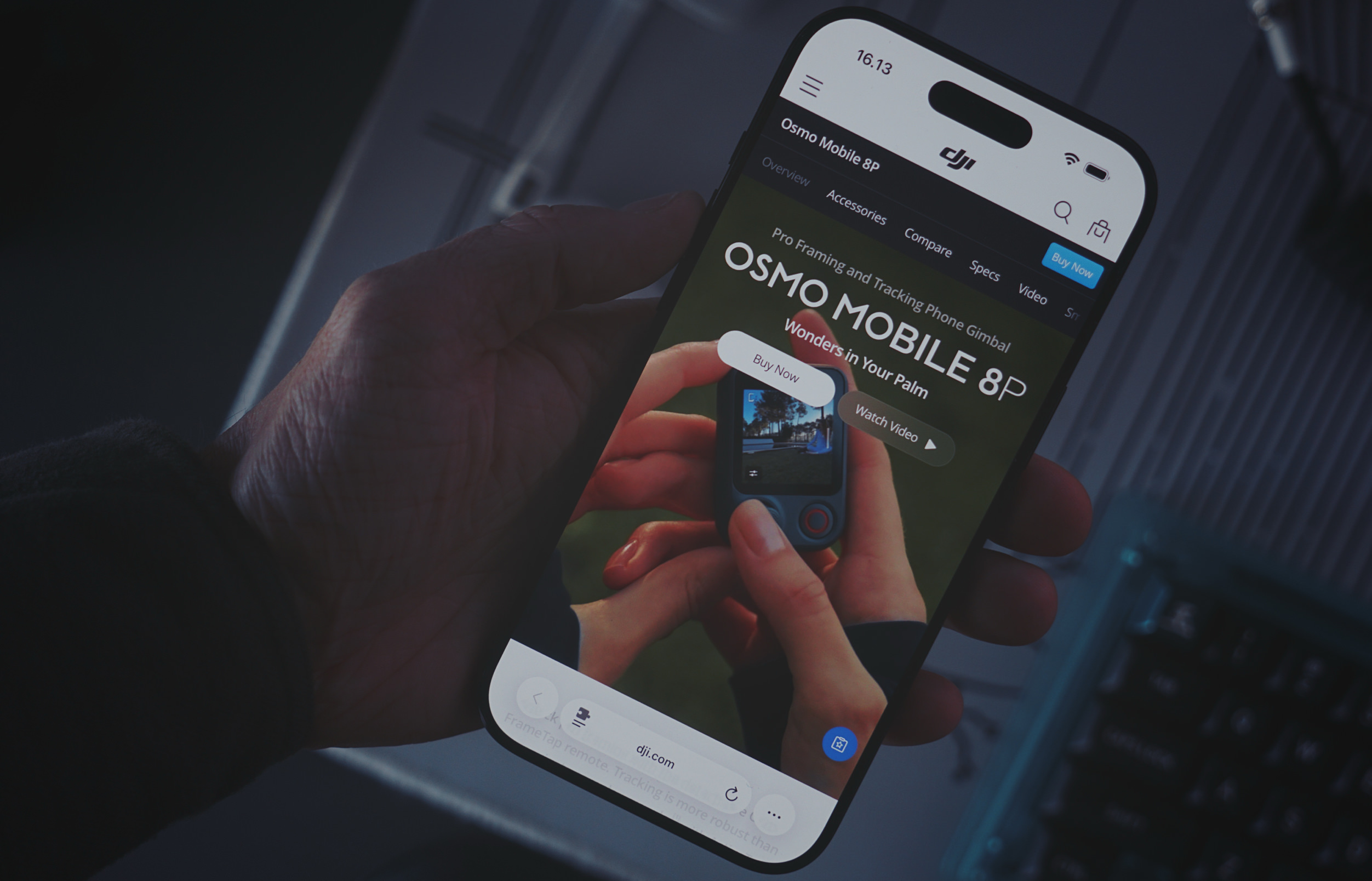 Eine Hand hält ein Smartphone, das die DJI-Produktseite für den Osmo Mobile 8P Gimbal anzeigt. Auf dem Bildschirm sind Produktinformationen zu sehen, darunter der Text: "16.13", "Osmo Mobile 8P", "Overview Accessories Compare Specs Video", "Buy Now", "Pro Framing and Tracking Phone Gimbal", "OSMO MOBILE 8P", "Wonders in Your Palm", "Buy Now", "Watch Video", "dji.com" und "Tap remote: Tracking is more robust than...".