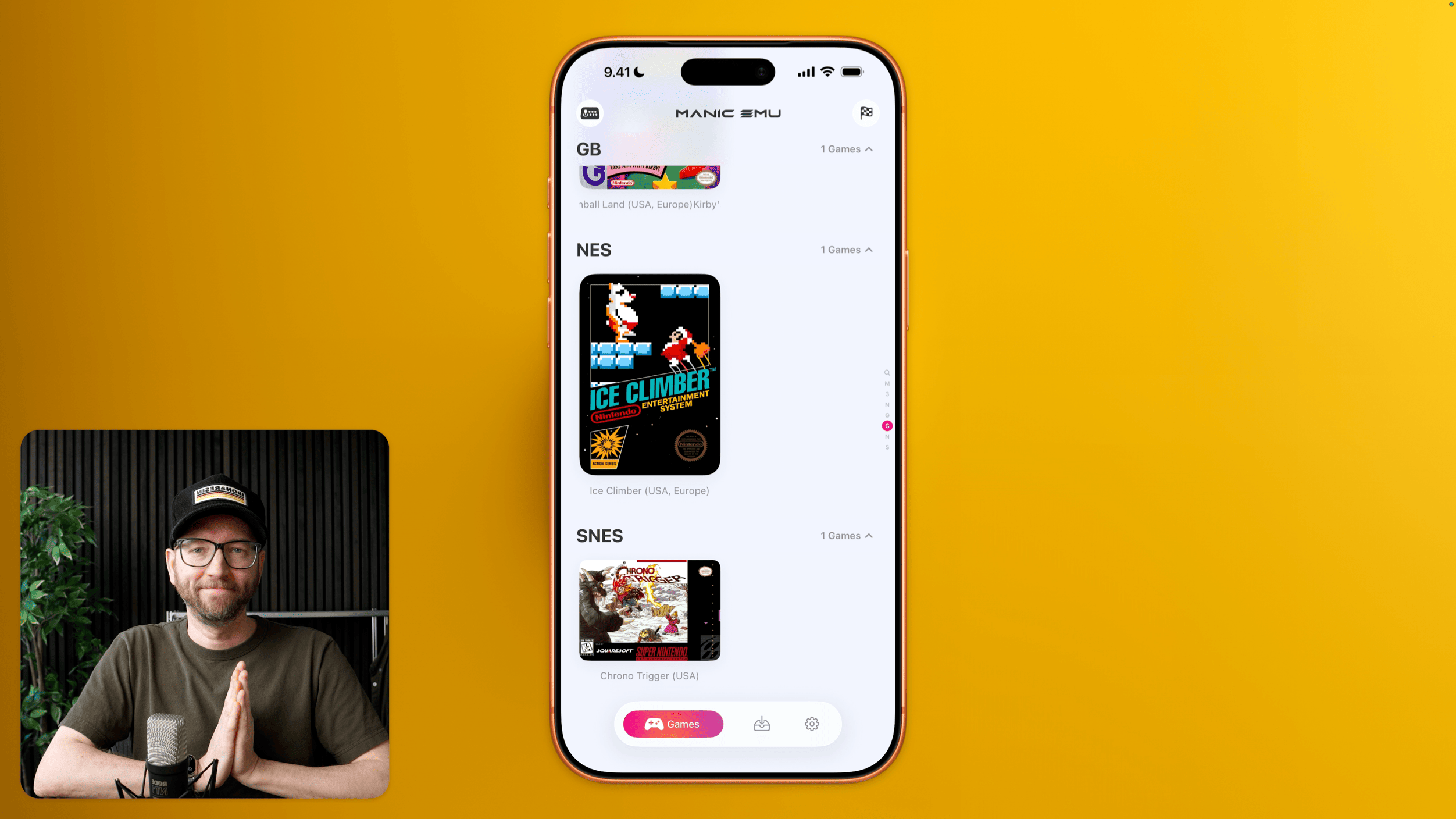 Ein Smartphone-Bildschirm vor gelbem Hintergrund zeigt die App „MANIC EMU“ mit den Spiele-Kategorien „GB“ (1 Games), „NES“ (1 Games) mit dem Cover-Bild für „ICE CLIMBER“ und „SNES“ (1 Games) mit dem Cover-Bild für „CHRONO TRIGGER“. Das untere Navigationsmenü zeigt die Beschriftung „Games“, ein Ordner-Symbol und ein Zahnrad-Symbol. In der linken unteren Ecke ist ein Video-Ausschnitt einer Person mit Brille und Kappe zu sehen, die mit gefalteten Händen vor einem Mikrofon sitzt.