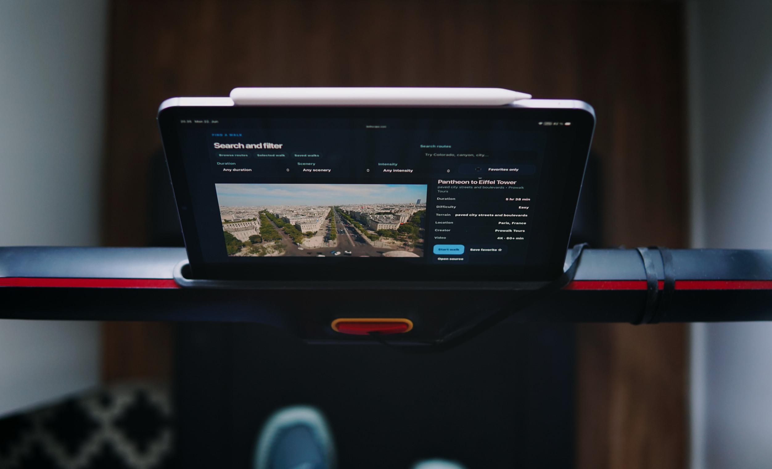 Ein Tablet, das auf dem Bedienfeld eines Laufbands montiert ist und eine virtuelle Wanderroute vom Pantheon zum Eiffelturm in Paris innerhalb einer Fitness-App anzeigt.