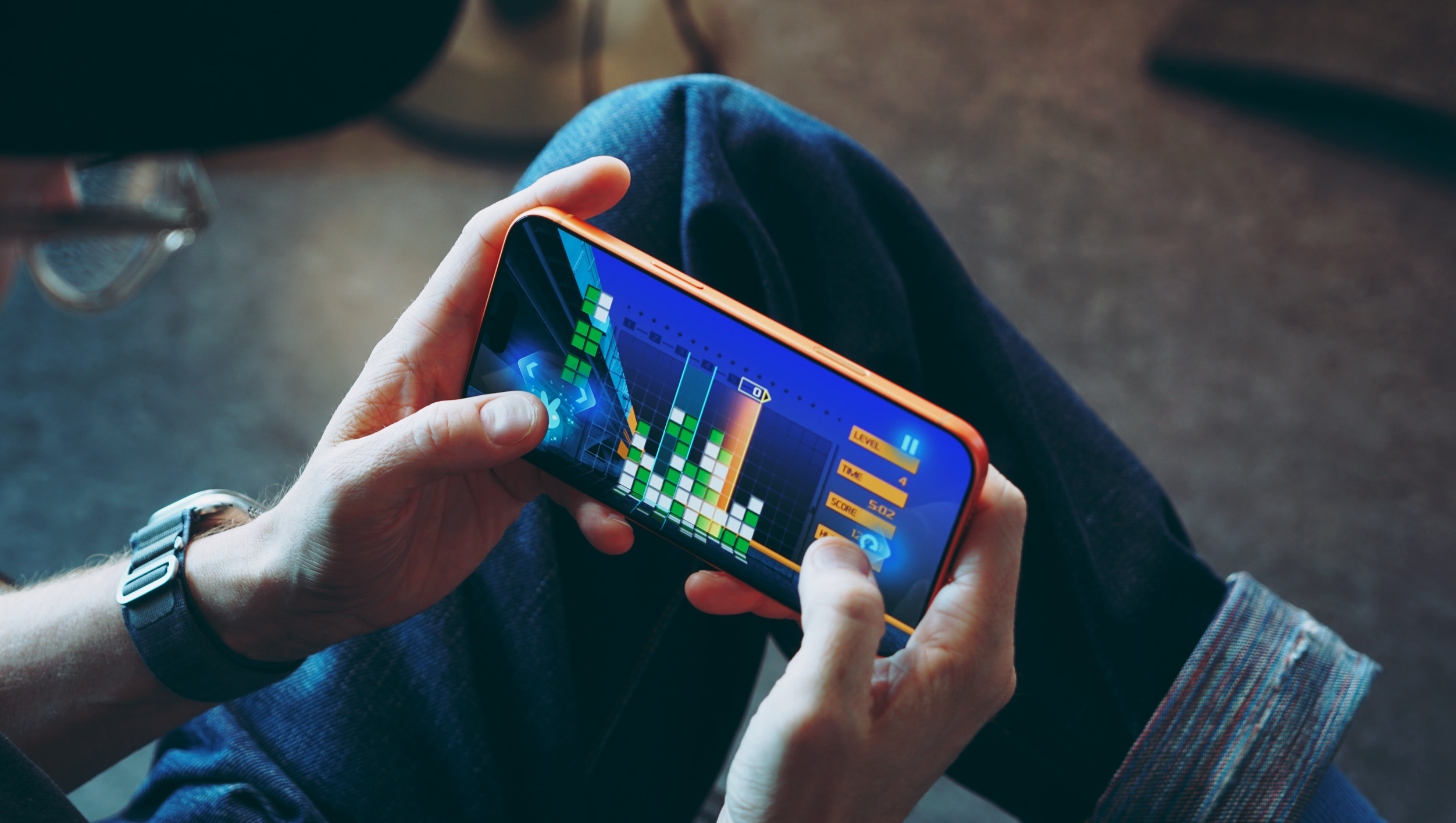 Nahaufnahme aus der Ich-Perspektive einer Person, die ein Block-Puzzle-Spiel auf einem Smartphone im Querformat spielt.