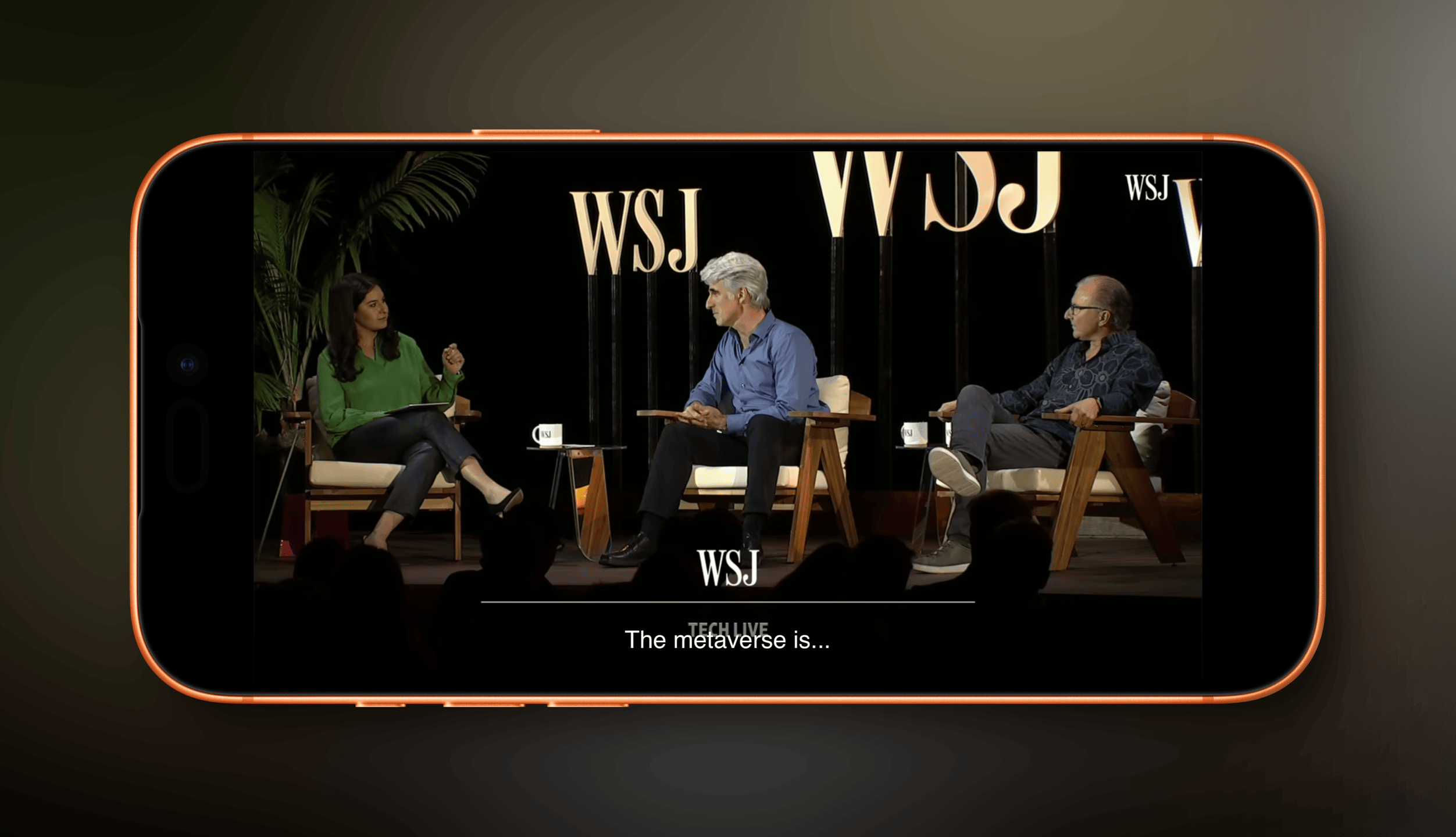 Drei Personen sitzen während einer Podiumsdiskussion auf einer Bühne in Sesseln, mit "WSJ"-Logos im Hintergrund. Die Szene ist von einem Smartphone-Rahmen umgeben, und am unteren Rand steht der Text „The metaverse is...“.