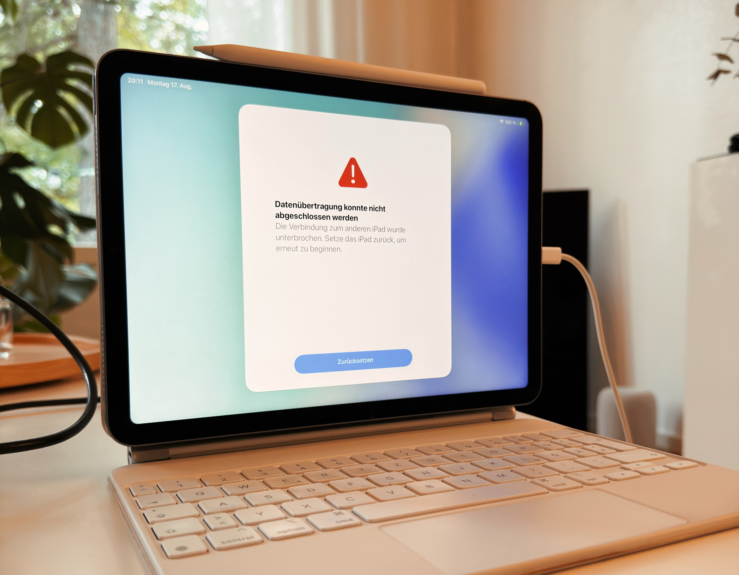 Ein iPad mit angeschlossener Tastatur zeigt auf dem Bildschirm eine Fehlermeldung, die besagt, dass die Datenübertragung aufgrund einer unterbrochenen Verbindung nicht abgeschlossen werden konnte, inklusive einer Schaltfläche zum Zurücksetzen.