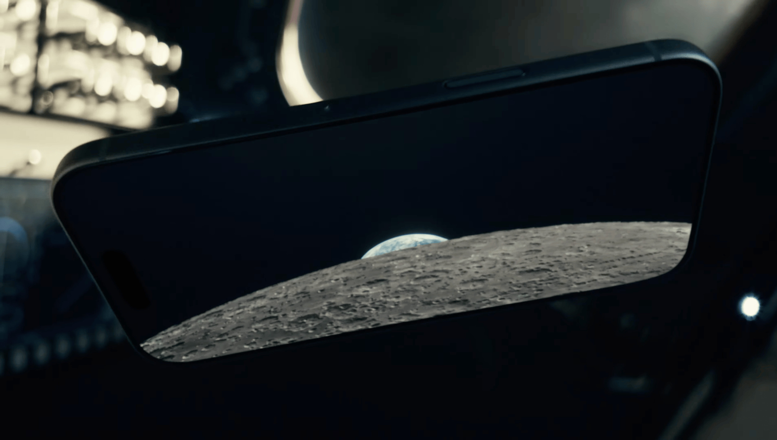 A close-up photograph of a smartphone screen displaying an image of the moon's surface rising against a dark sky.